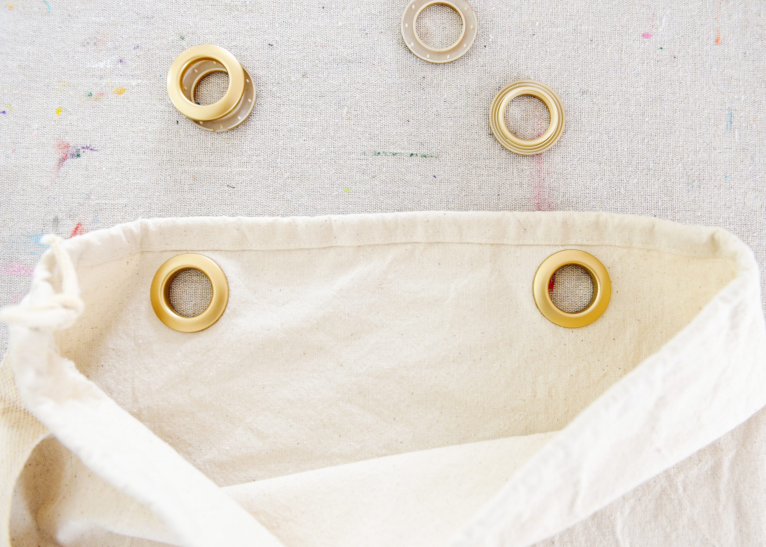 Adding the grommets to the laundry bags | A DIY Laundry Sorter Solution, via Yellow Brick Home