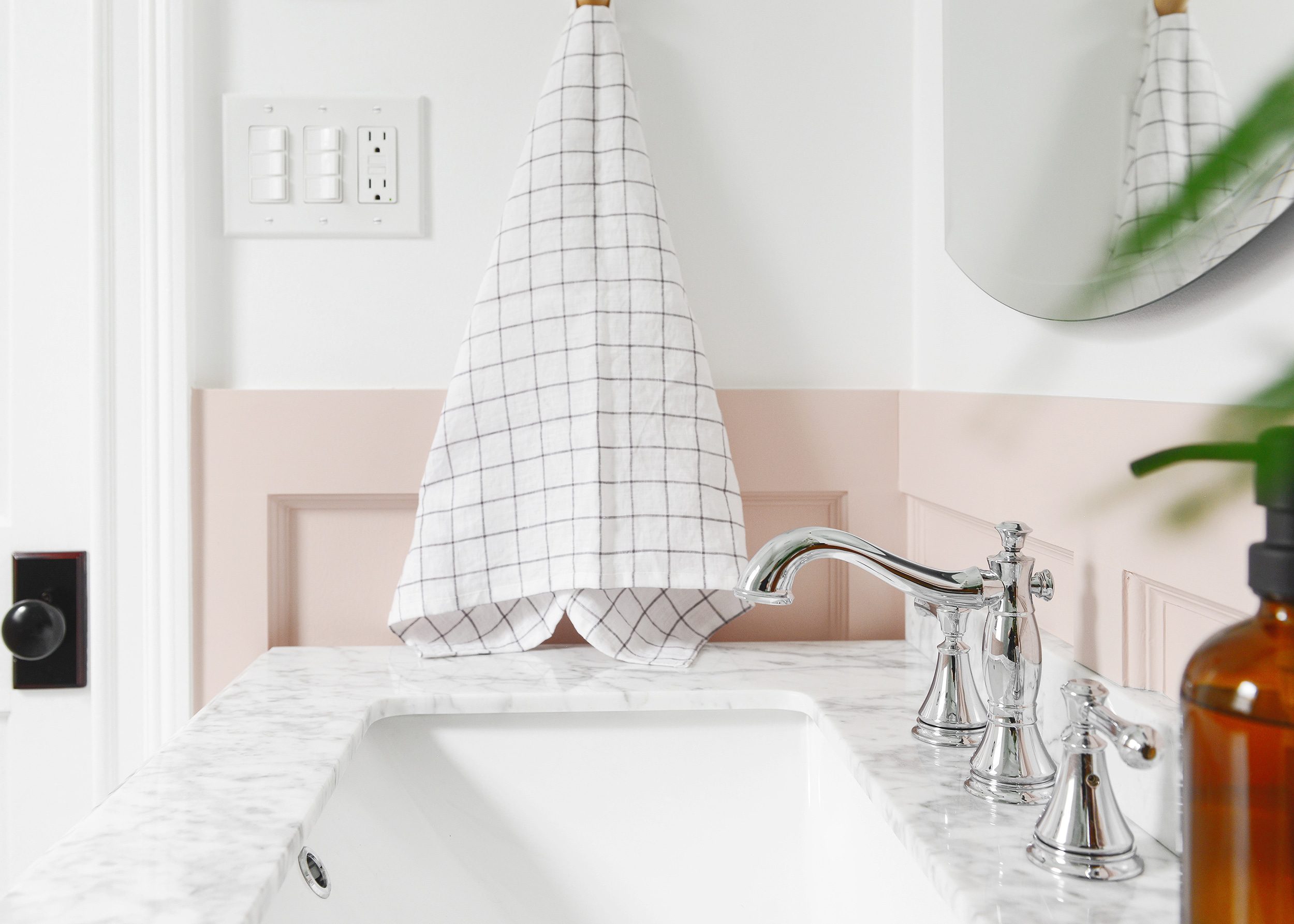 A pink bathroom with polished chrome faucet and windowpane grid hand towel | via Yellow Brick Home