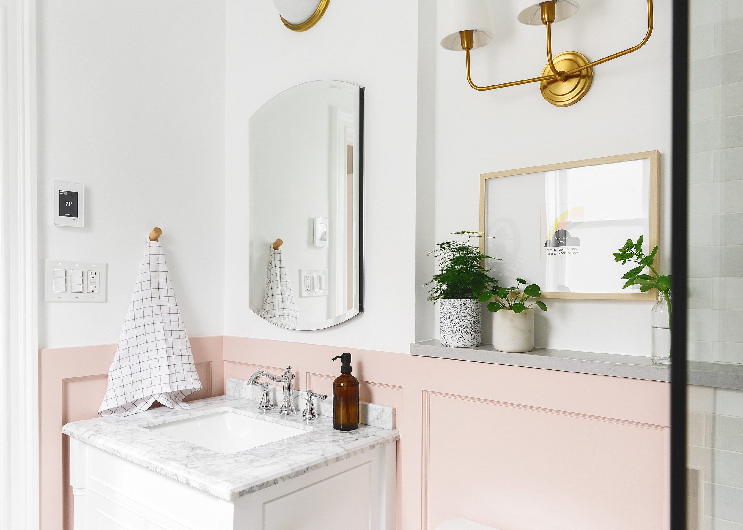 A pink and white bathroom with brass accents | art in a bathroom | round-up of 19 works of art that would look good in a bathroom, via Yellow Brick Home