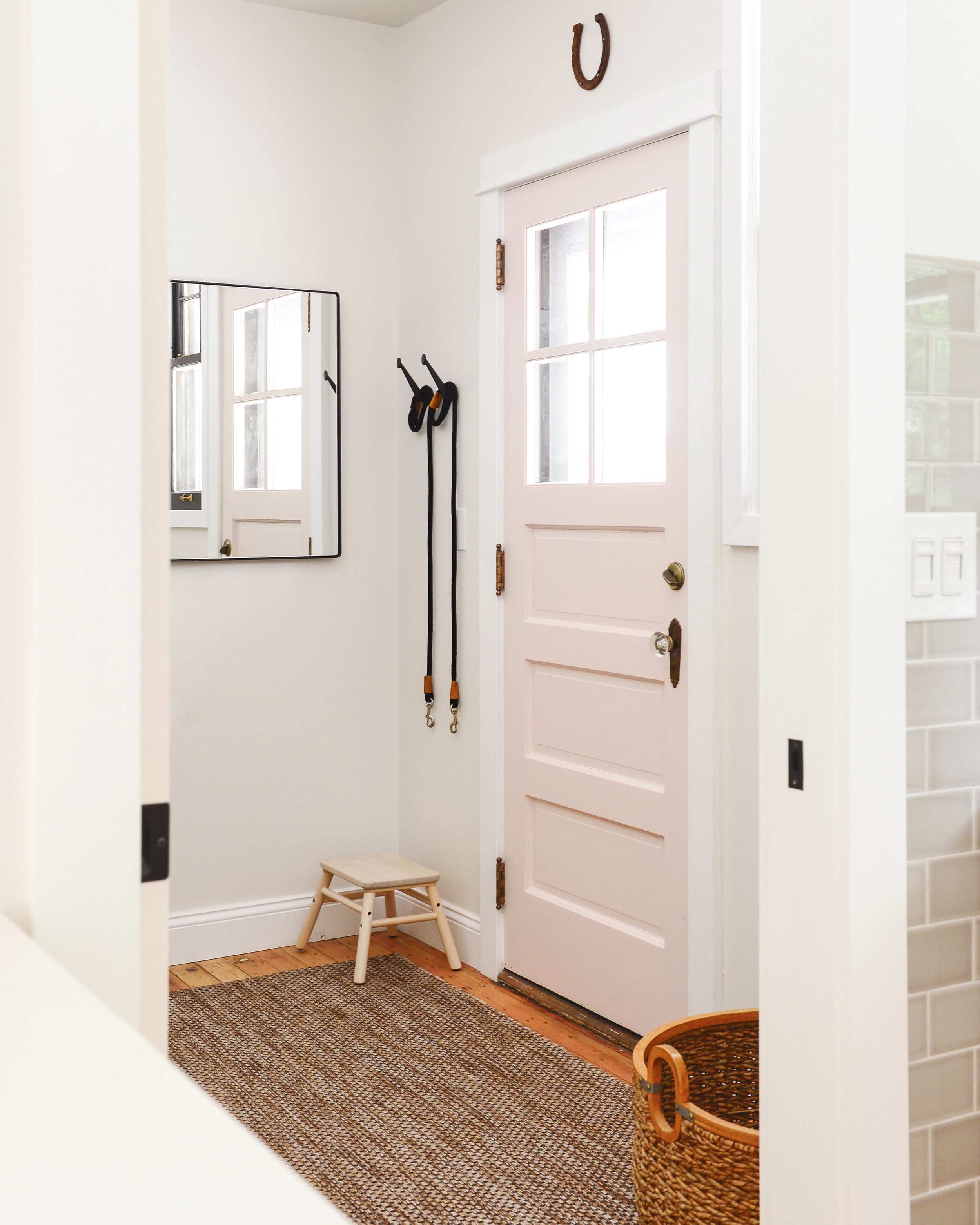 A simple mudroom with a soft pink door and outdoor rug, via Yellow Brick Home