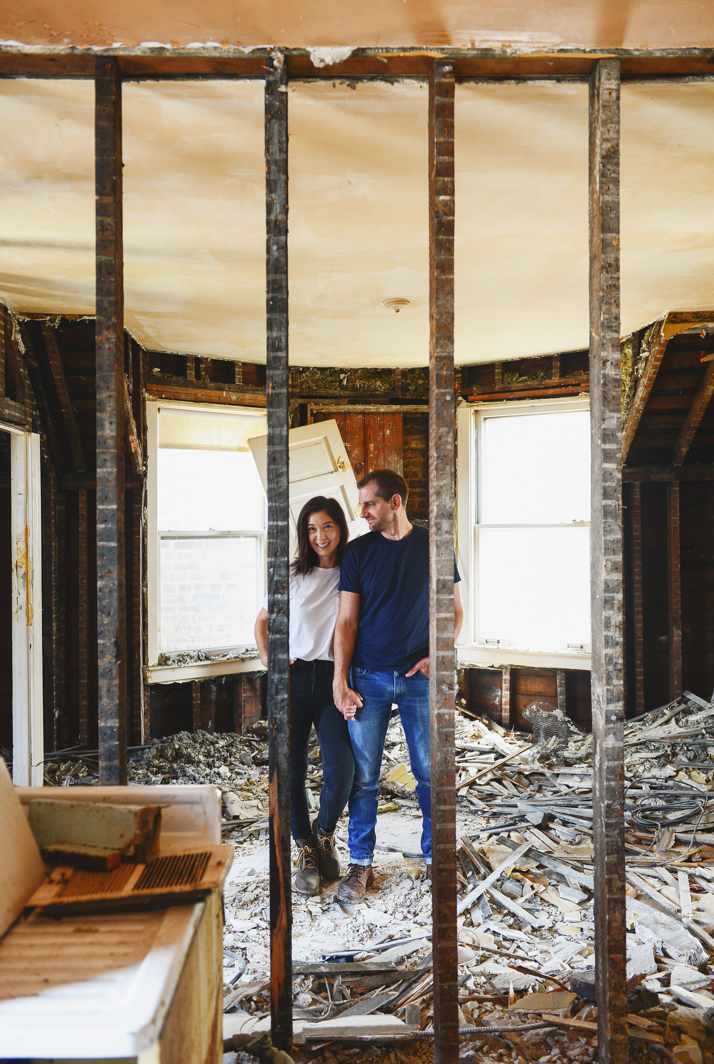 Kim and Scott standing on a pile of rubble inside the Two Flat with exposed wall studs in the foreground | Our goals for 2020, the best is yet to come! via Yellow Brick Home