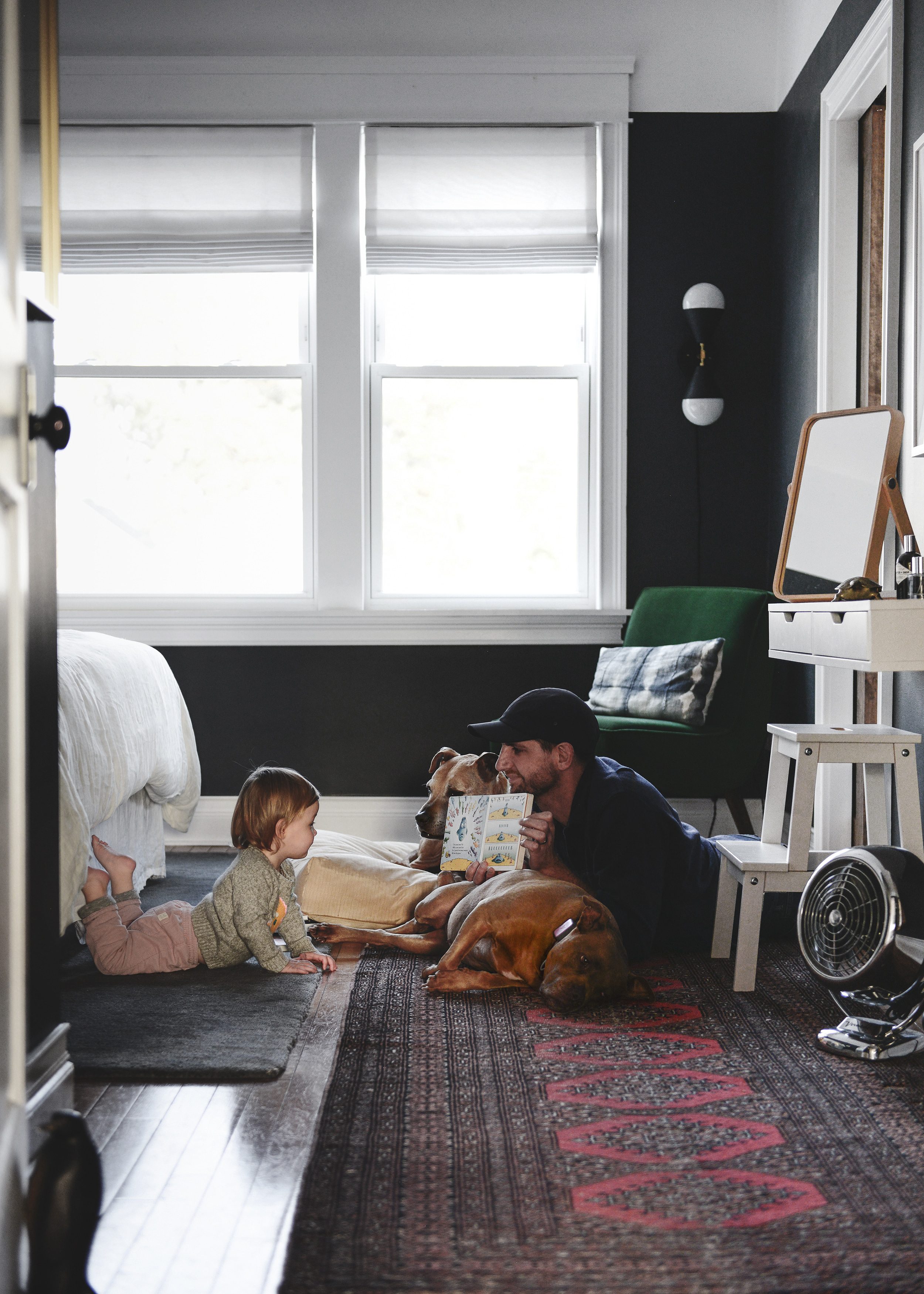 Dad reading toddler a book with two dogs by their side | Lucy's toddler schedule at 22 months old | via Yellow Brick Home