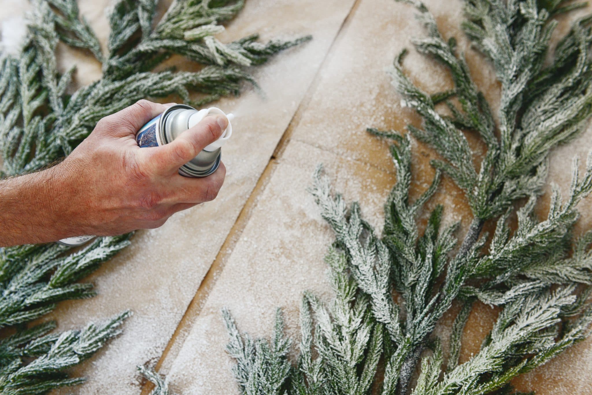 Detail shot of spraying Sno Blast on two strands of faux garland | Which flocking spray is best? | How to flock your own holiday garland, tree and decor, via Yellow Brick Home