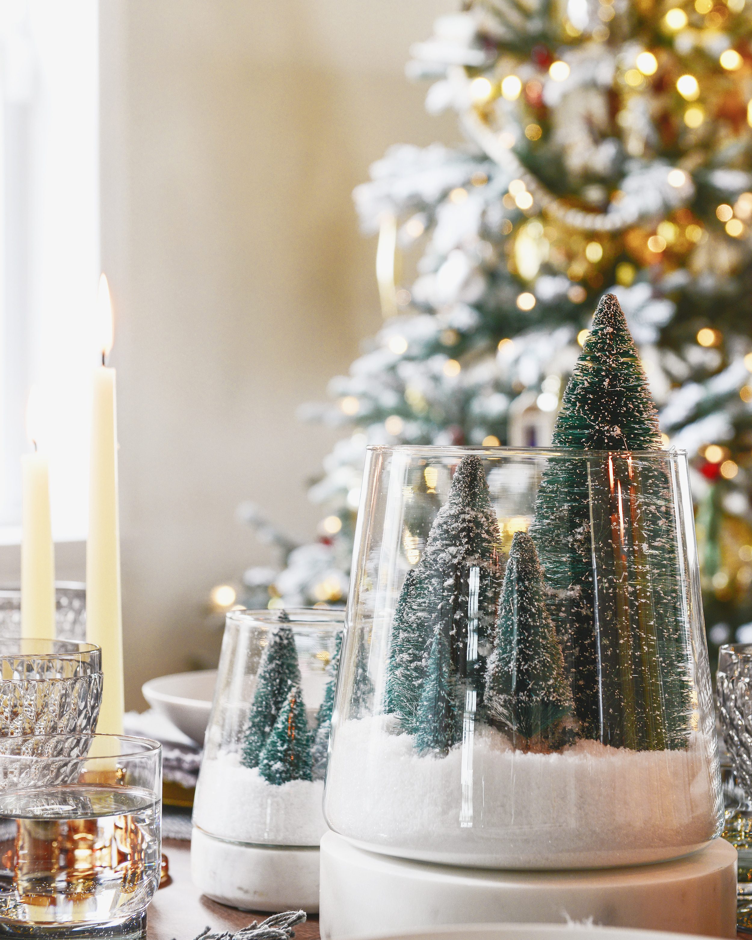 A close up of a DIY table centerpiece made from flocked trees and a hurricane glass | This holiday season, consider simplifying your table setting with these 5 fresh styling tips! | via Yellow Brick Home