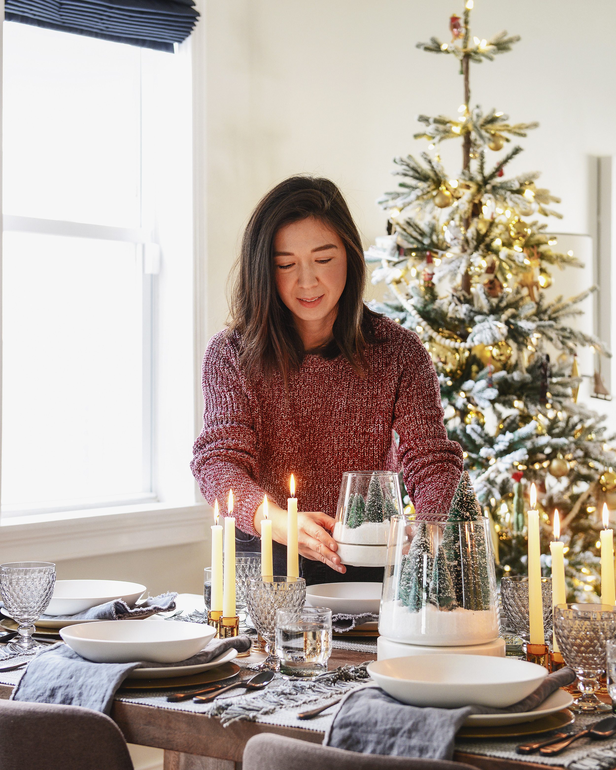 Homeowner setting down a centerpiece on the holiday themed dining table | This holiday season, consider simplifying your table setting with these 5 fresh styling tips! | via Yellow Brick Home