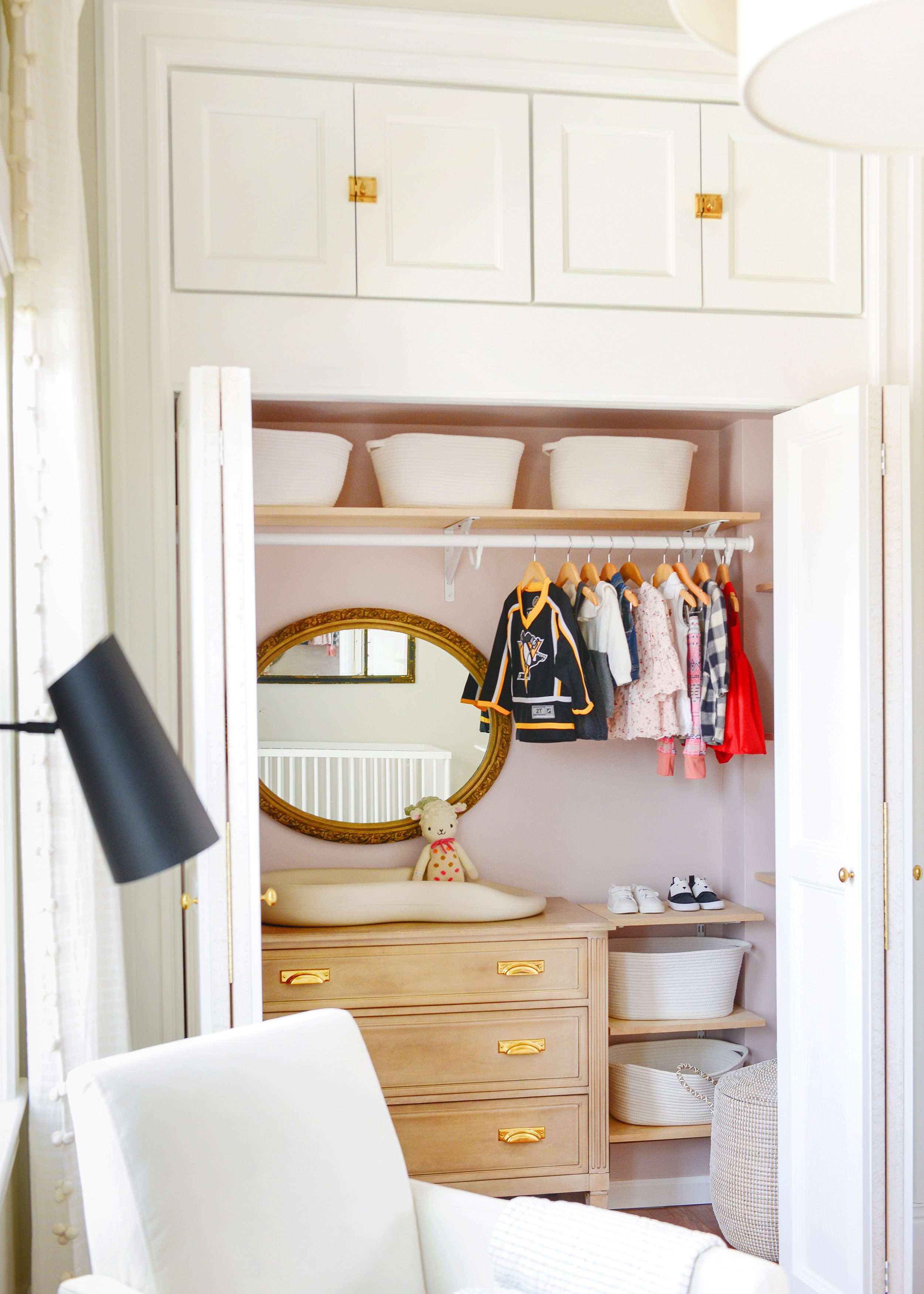 A closet with open doors showcases a light wood tone dresser and toddler clothing hung on hangers  // updates on our most popular projects via Yellow Brick Home