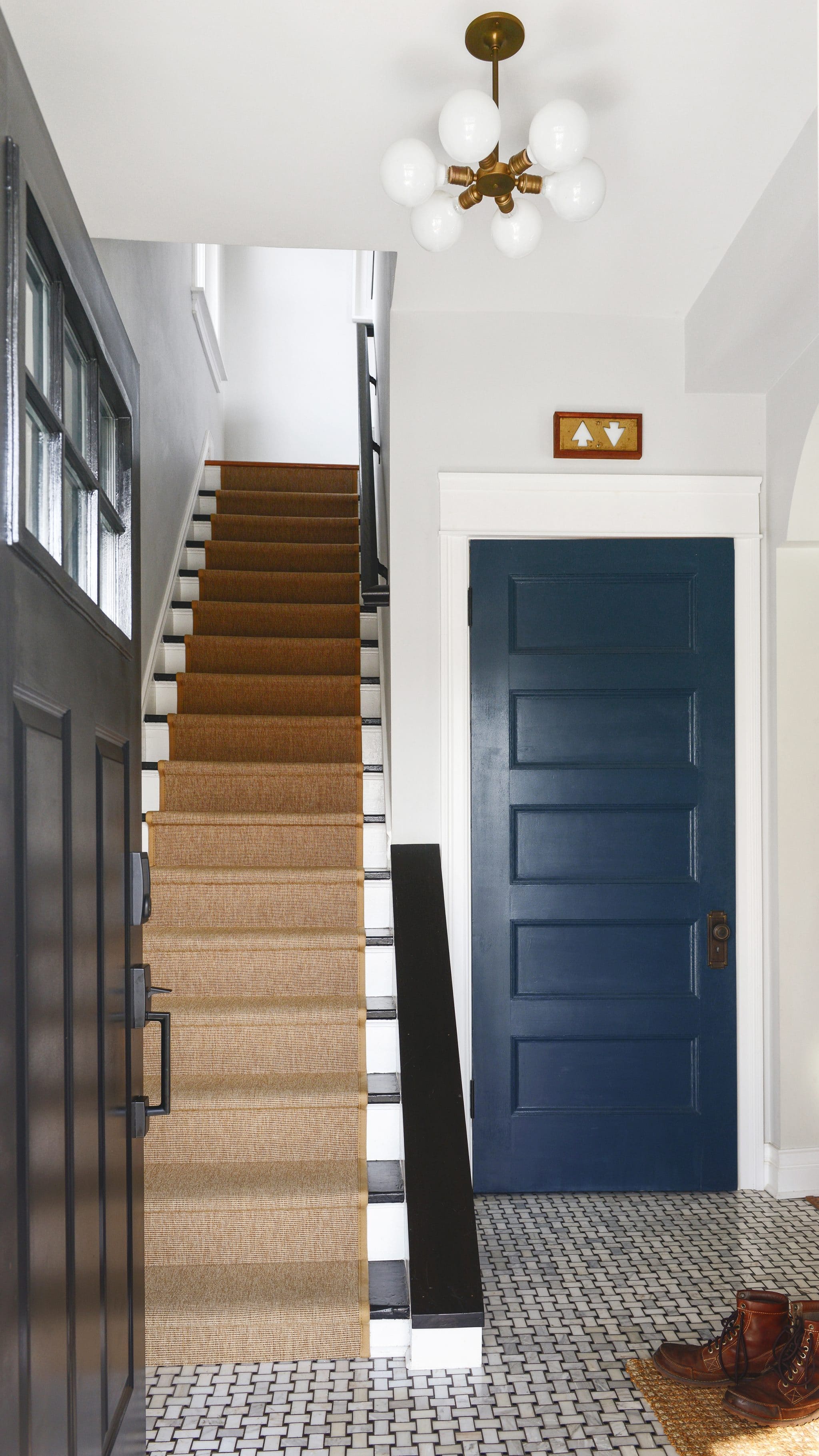 A classically modern entryway with a black front door, blue closet door and black and white stairs with runner // updates on our most popular projects via Yellow Brick Home