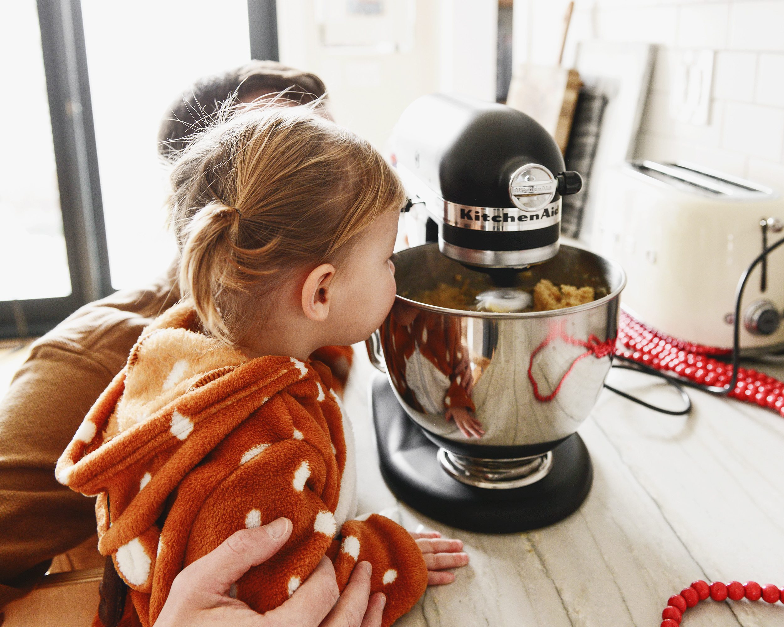 Scott and Lucy peer over the edge of a KitchenAid mixer to ensure the cookies are looking good! The best chocolate chip cookie recipe via Yellow Brick Home