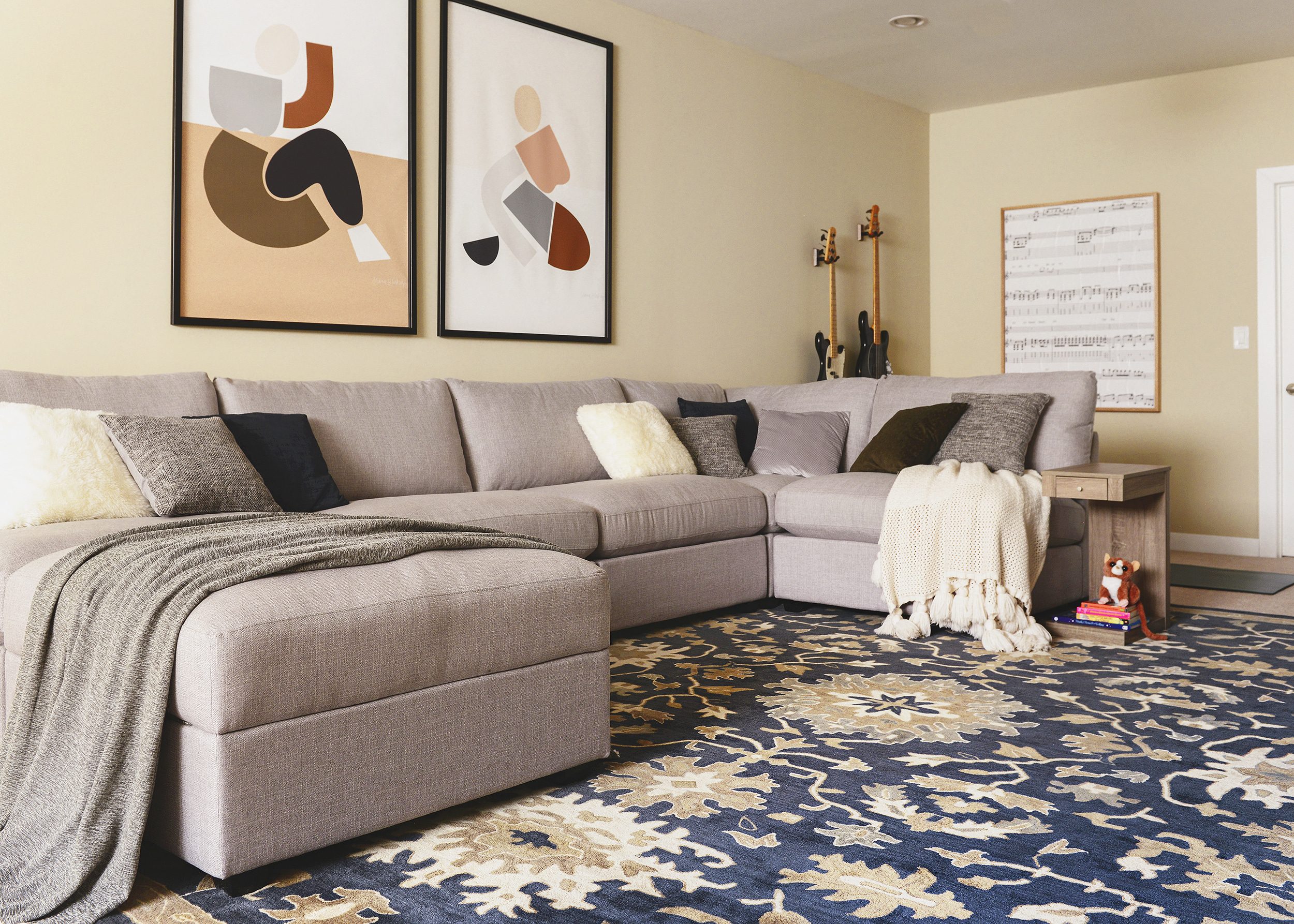 Neutral living room with large diptych and gray sectional with navy rug | via Yellow Brick Home