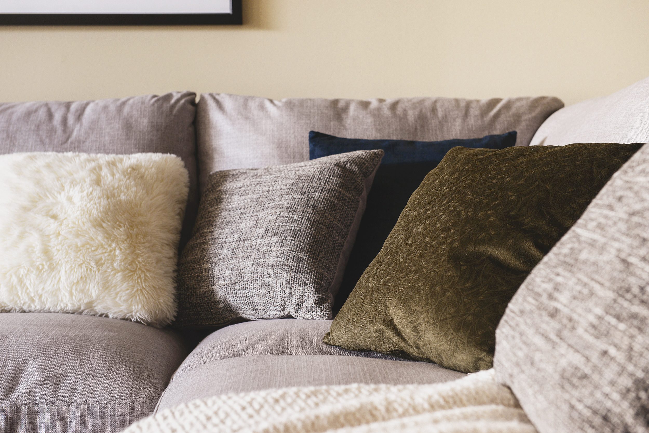 A gray sectional overflowing with flokati, tweed, moss and velvet pillows | via Yellow Brick Home