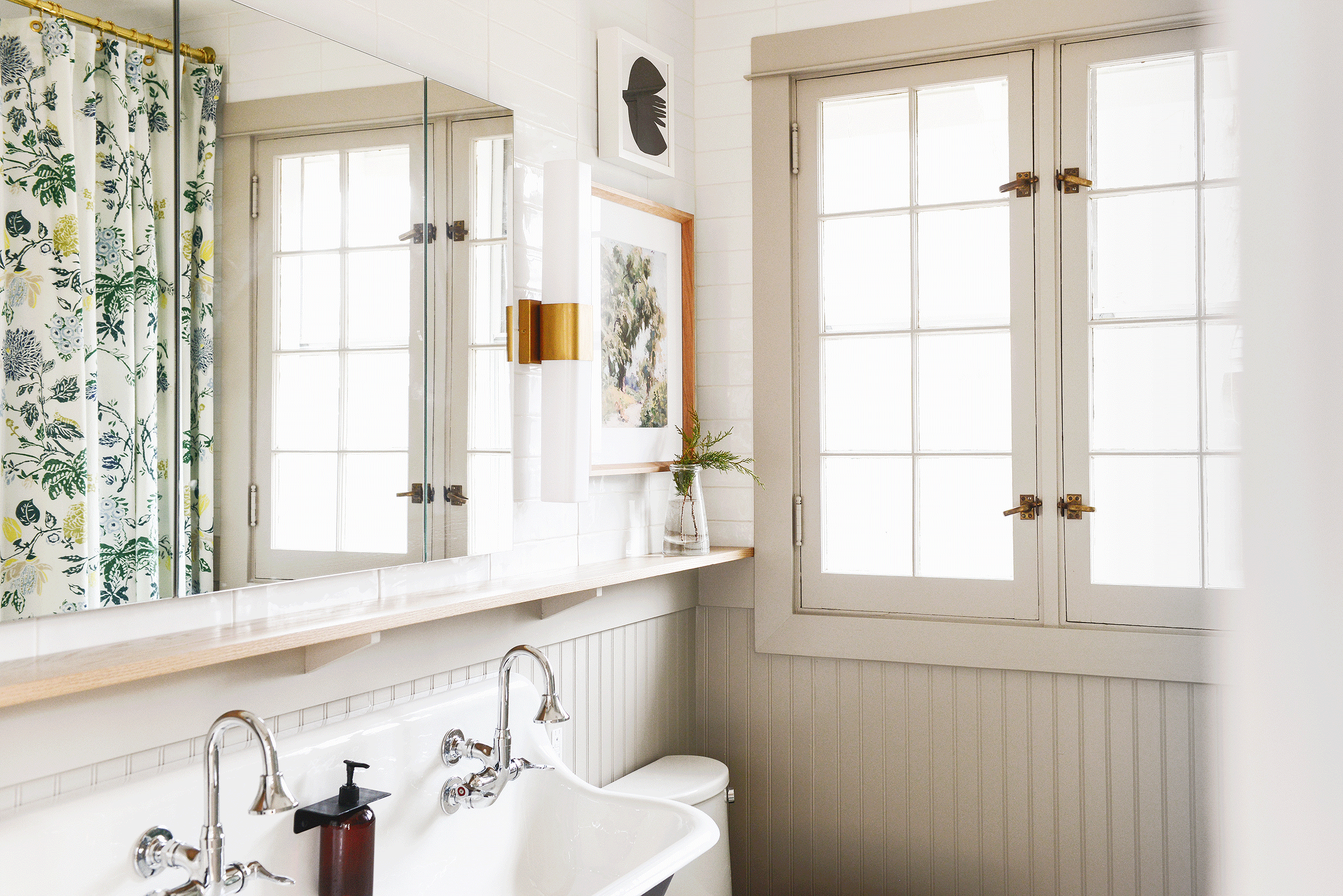 A GIF shows large mirrored medicine cabinet doors opening and closing in a green and tan bathroom // via Yellow Brick Home