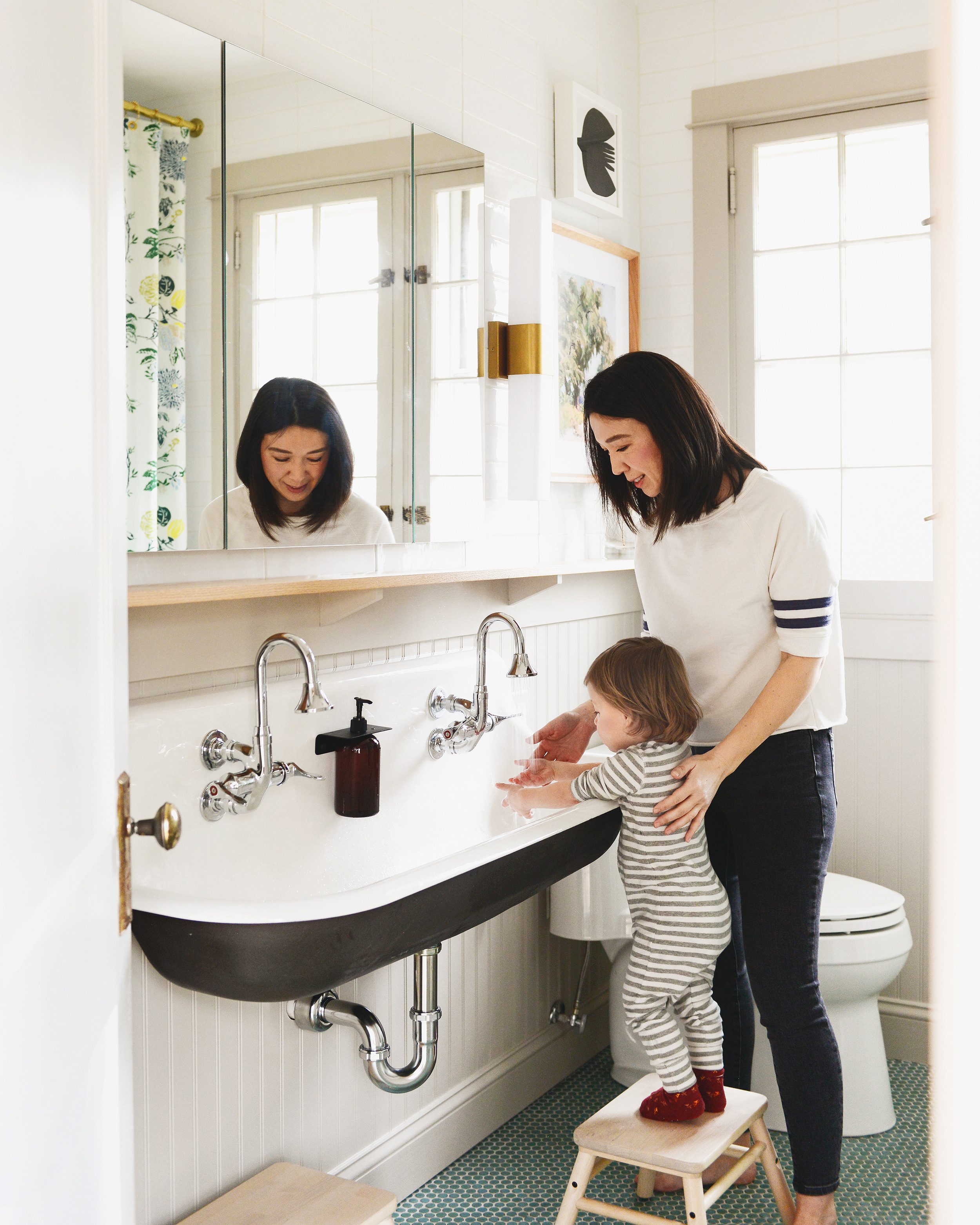 A mother and daughter wash their hands together in a large white basin sink in a tan and green bathroom.// via Yellow Brick Home