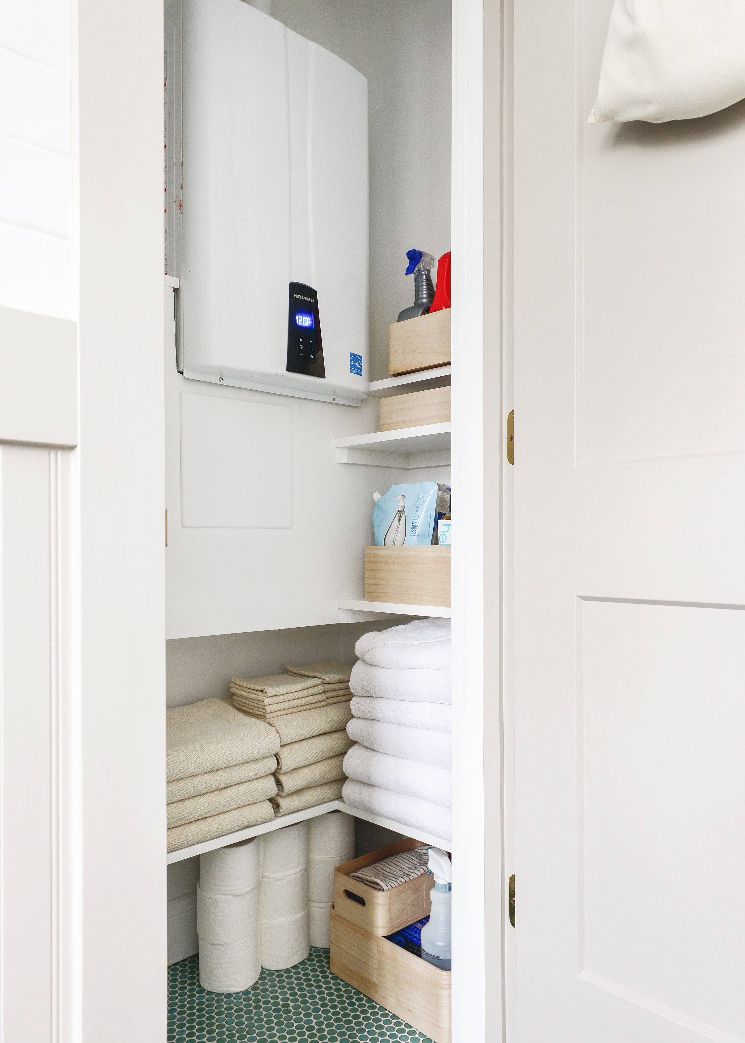 A finished linen closet contains a hot water heater and loads of built in storage // via Yellow Brick Home