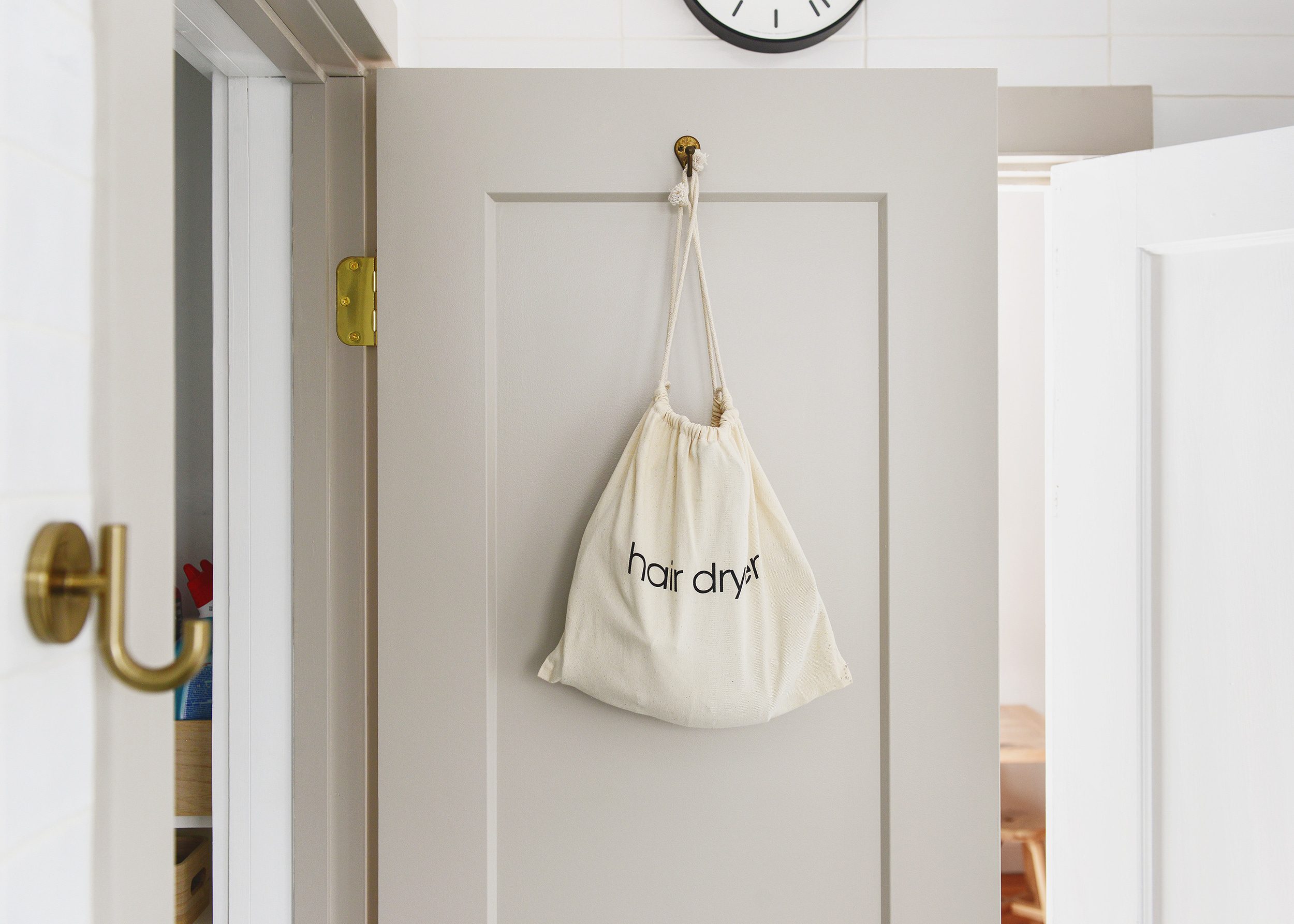 A canvas bag labeled 'hair dryer' hangs on the back of a linen closet door // via Yellow brick Home