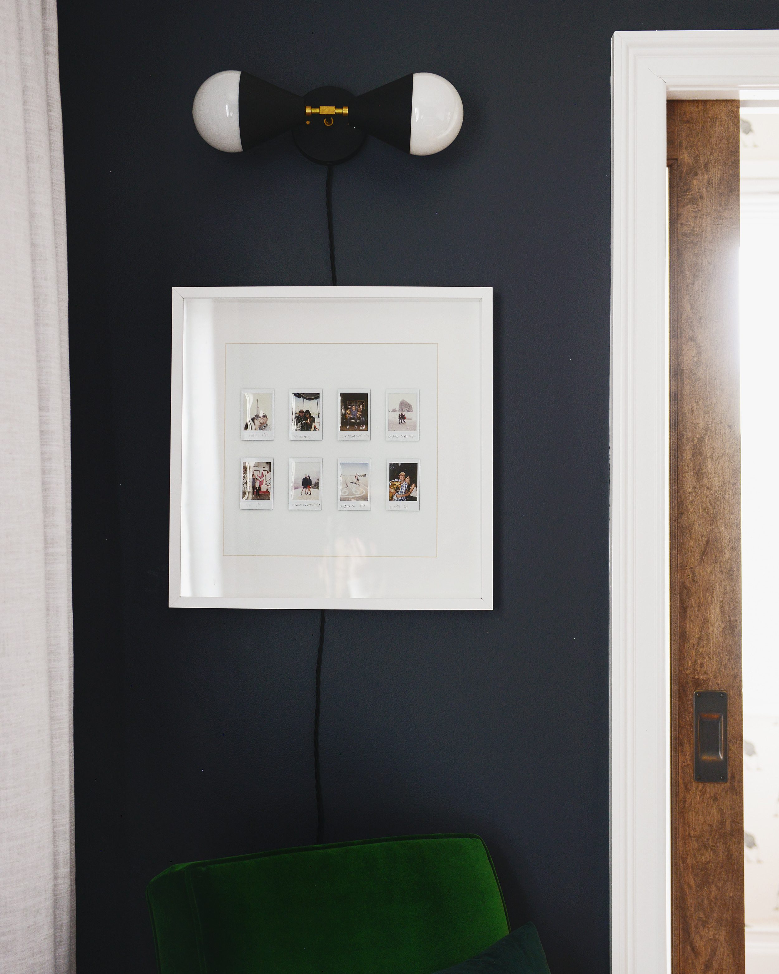 Instant photo frame display against a black wall in a bedroom | via Yellow Brick Home