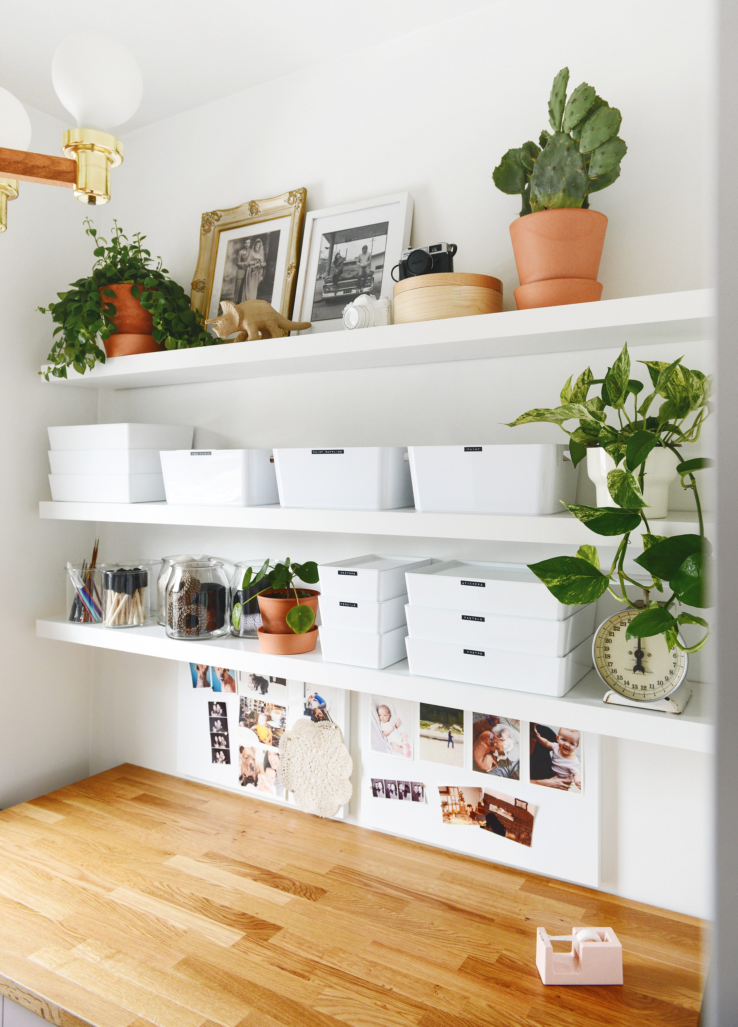 An organized craft room with a pink hutch and floating white IKEA LACK shelves with plants and storage! via Yellow Brick Home
