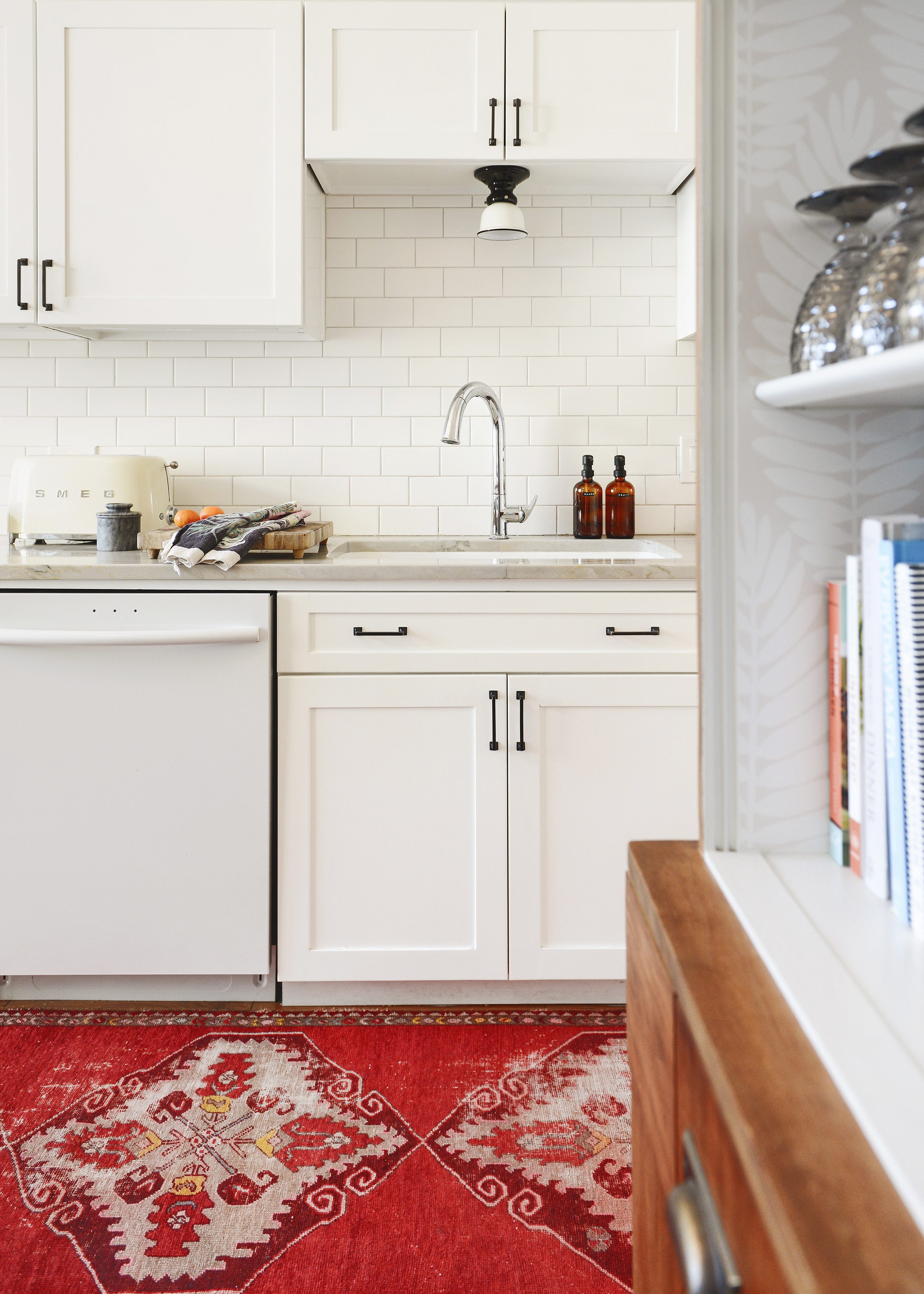 White kitchen with red vintage runner, chrome faucet and oil rubbed bronze hardware. | via Yellow Brick Home