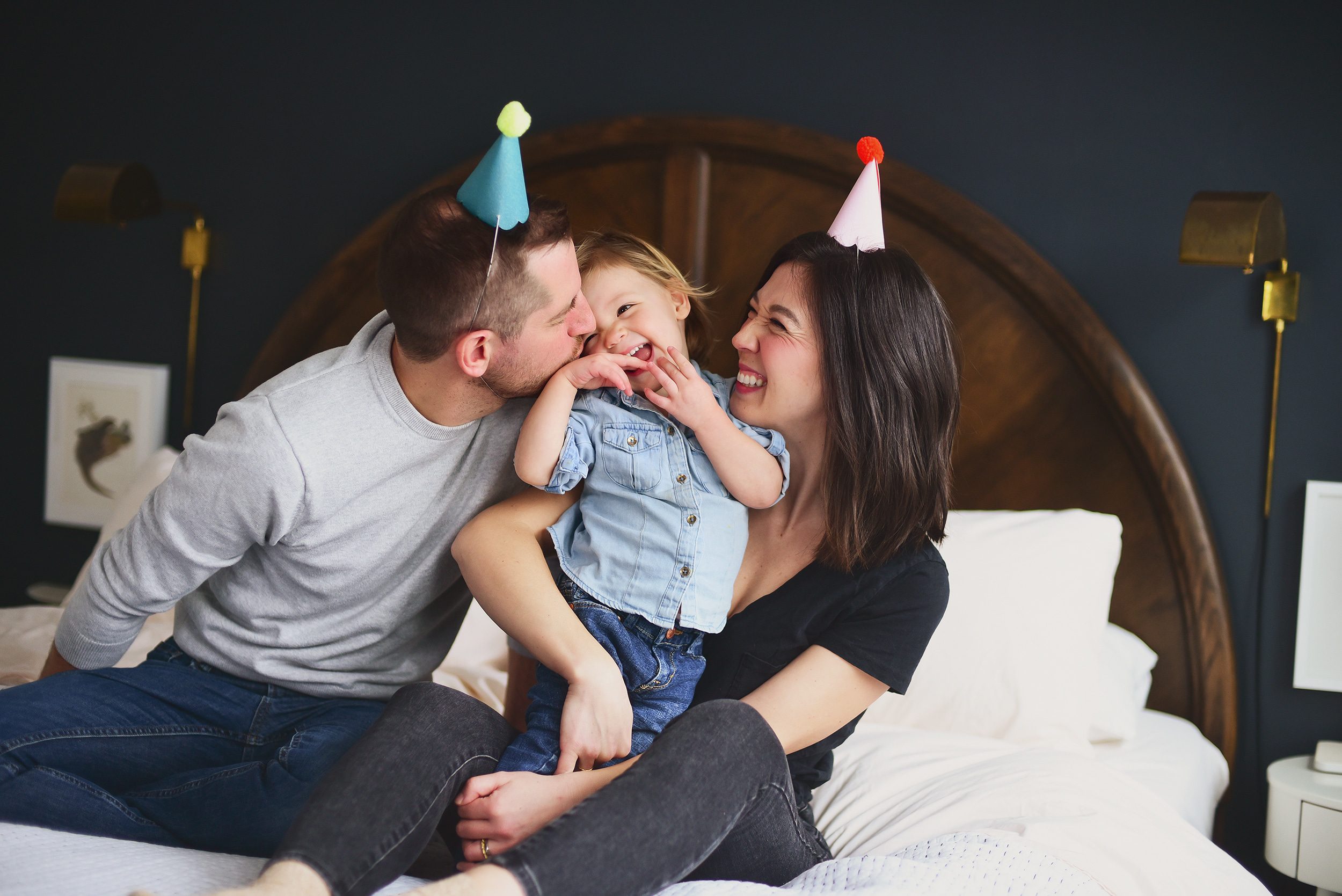 Family laughing on the bed, toddler smiling in-between mom and dad | How we choose, shop and keep our toddler's clothing under control | via Yellow Brick Home