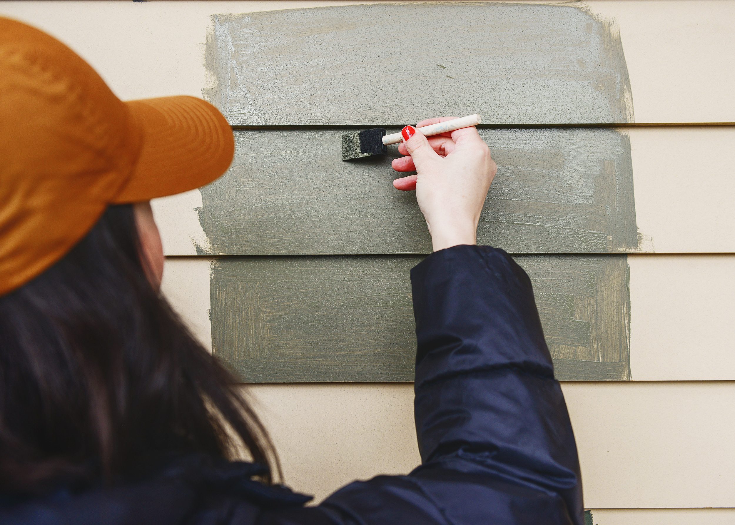 Olive green paint samples are applied to new siding with sponge brushes // via Yellow Brick Home