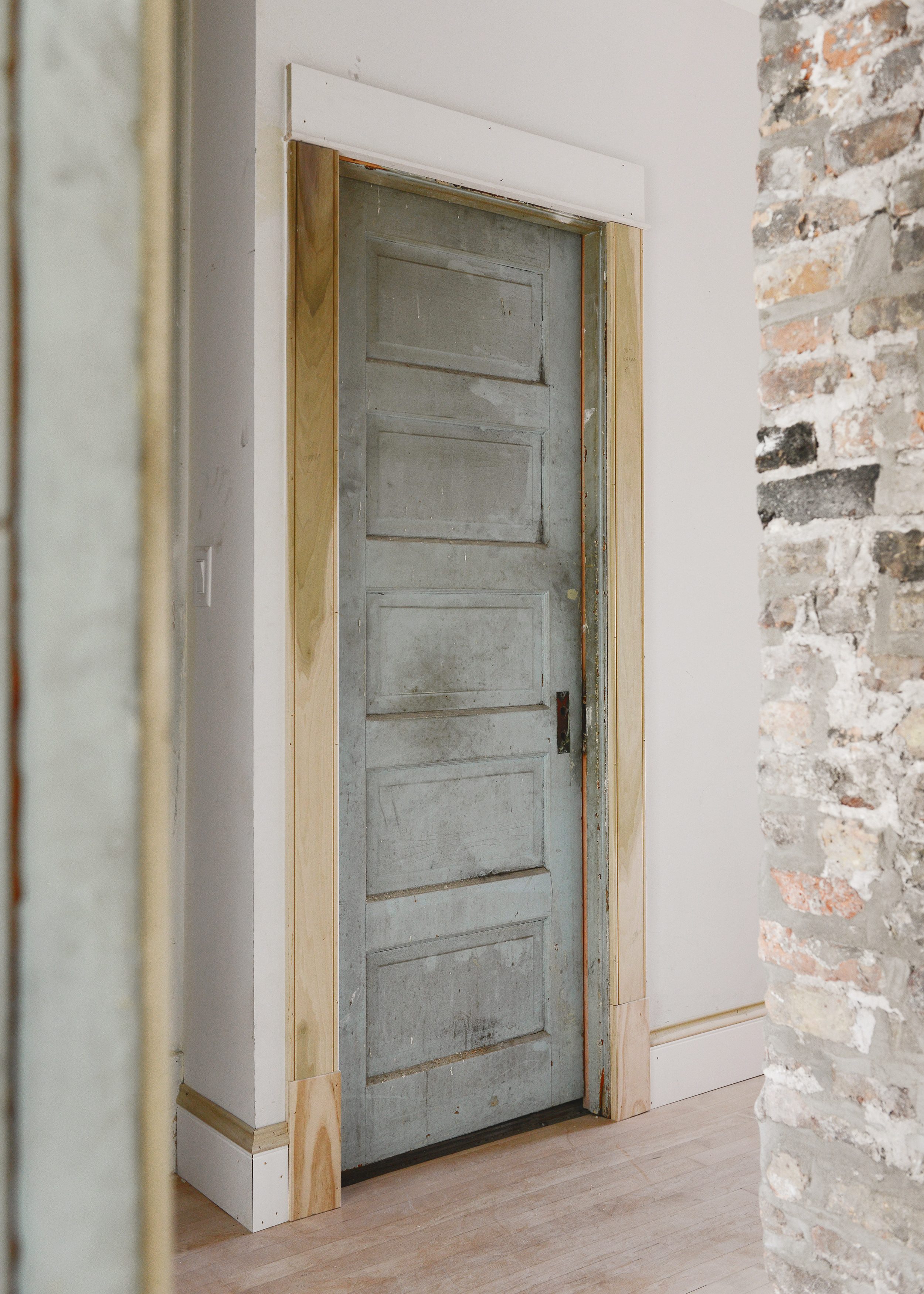A view of a 5 panel door with new millwork and a brick chimney nearby | via Yellow Brick Home