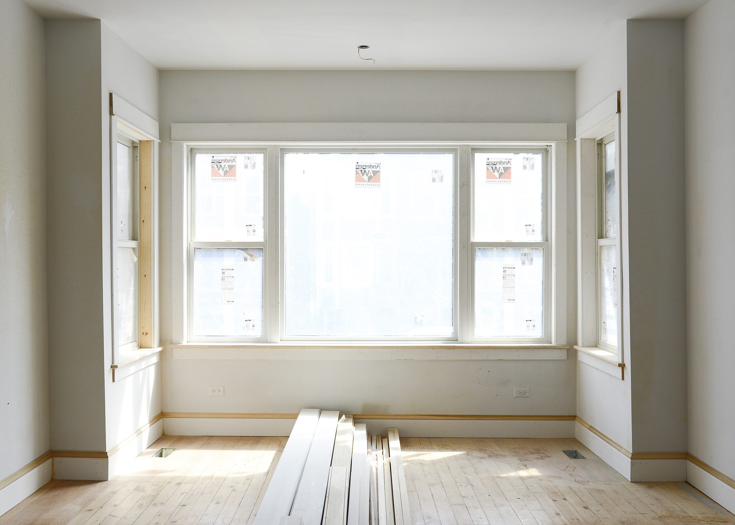 A large three-sided bay window is freshly trimmed with new millwork // via yellow brick home