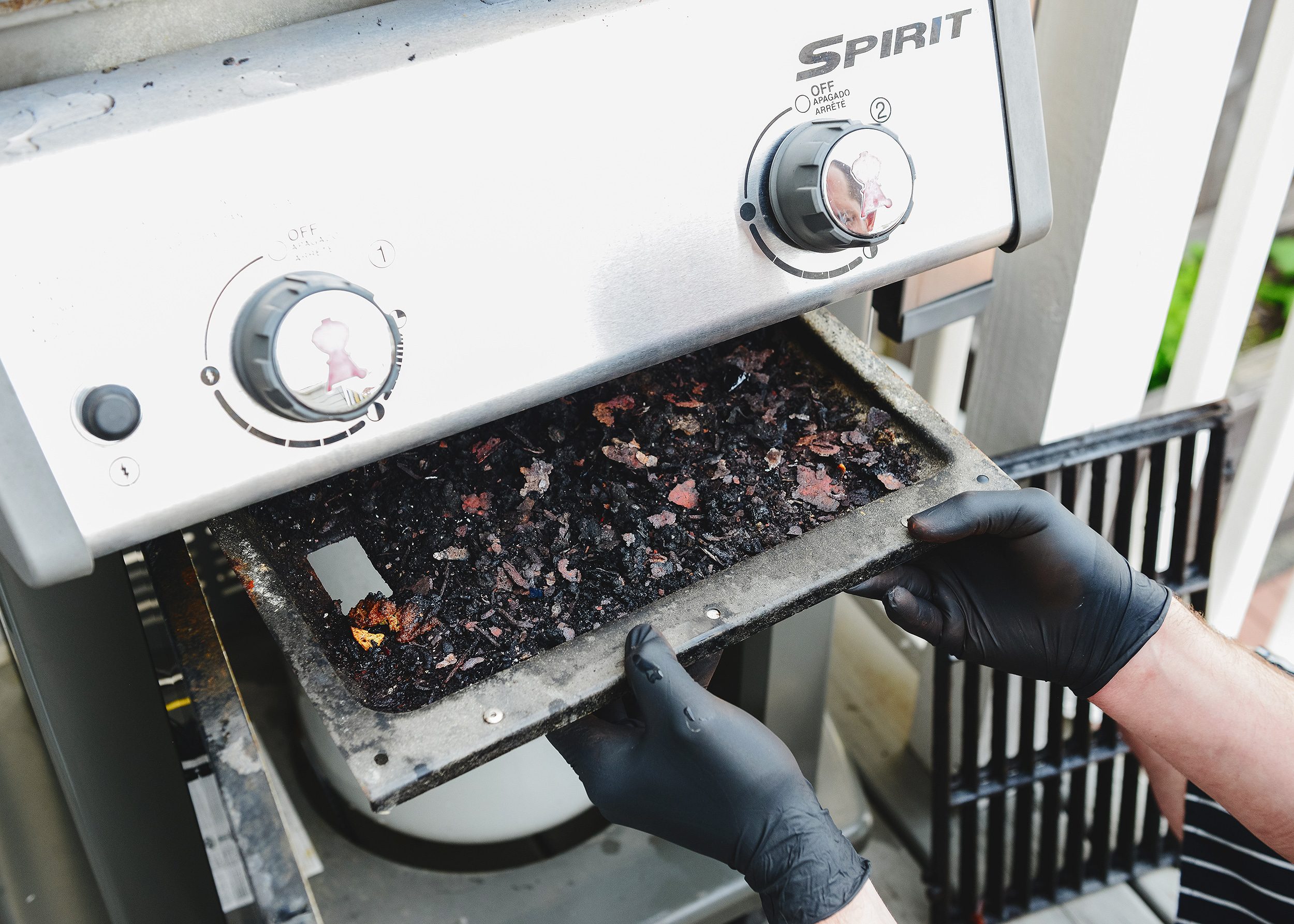 The overflowing grease try is removed from a Weber Spirit 210 gas grill // via yellow brick home