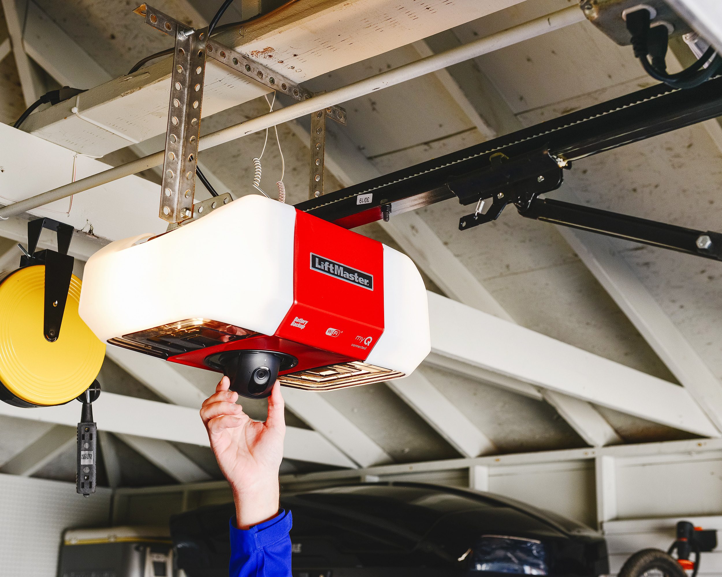 The camera of a liftmaster secure view garage door opener is adjusted by a man's hand // via yellow brick home 