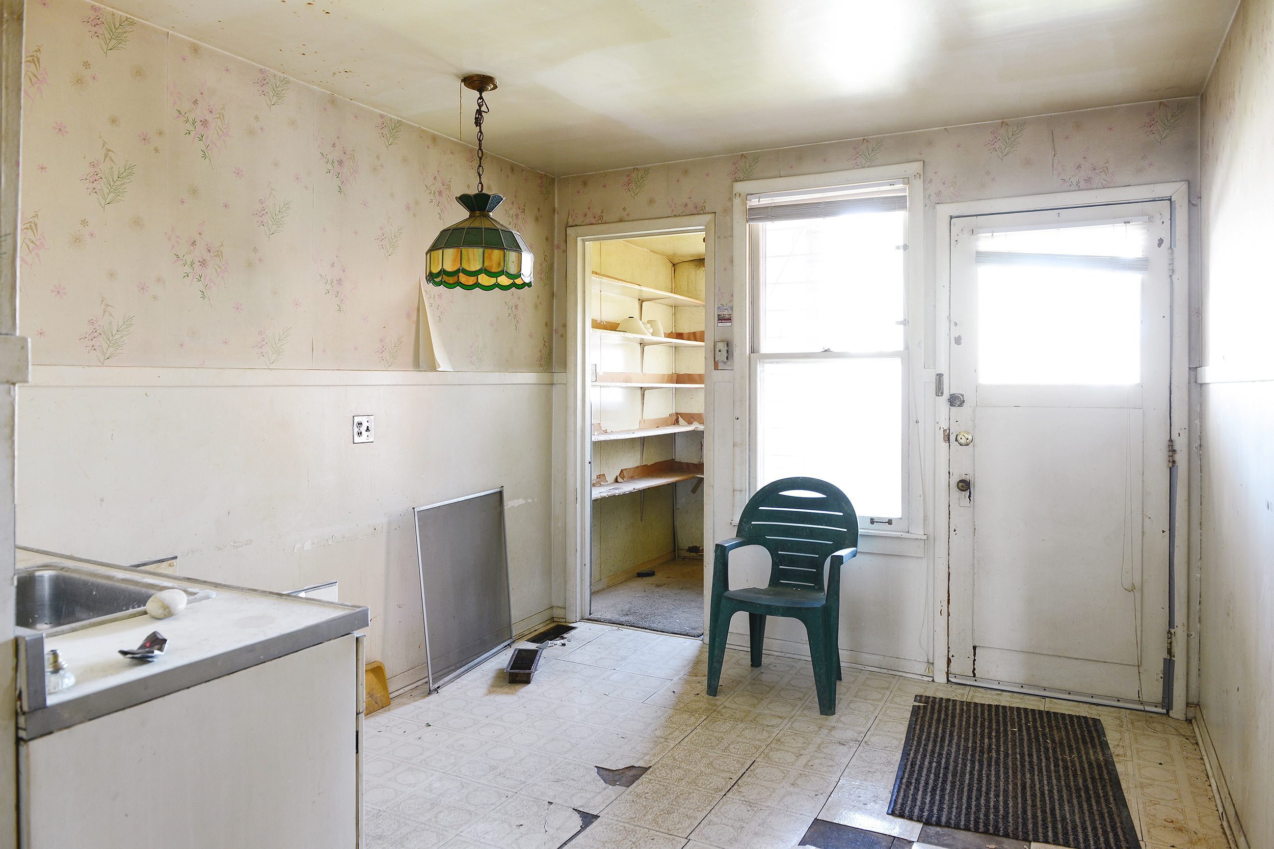 A 'before' photo of a vintage kitchen with peeling wallpaper and floors // via yellow brick home