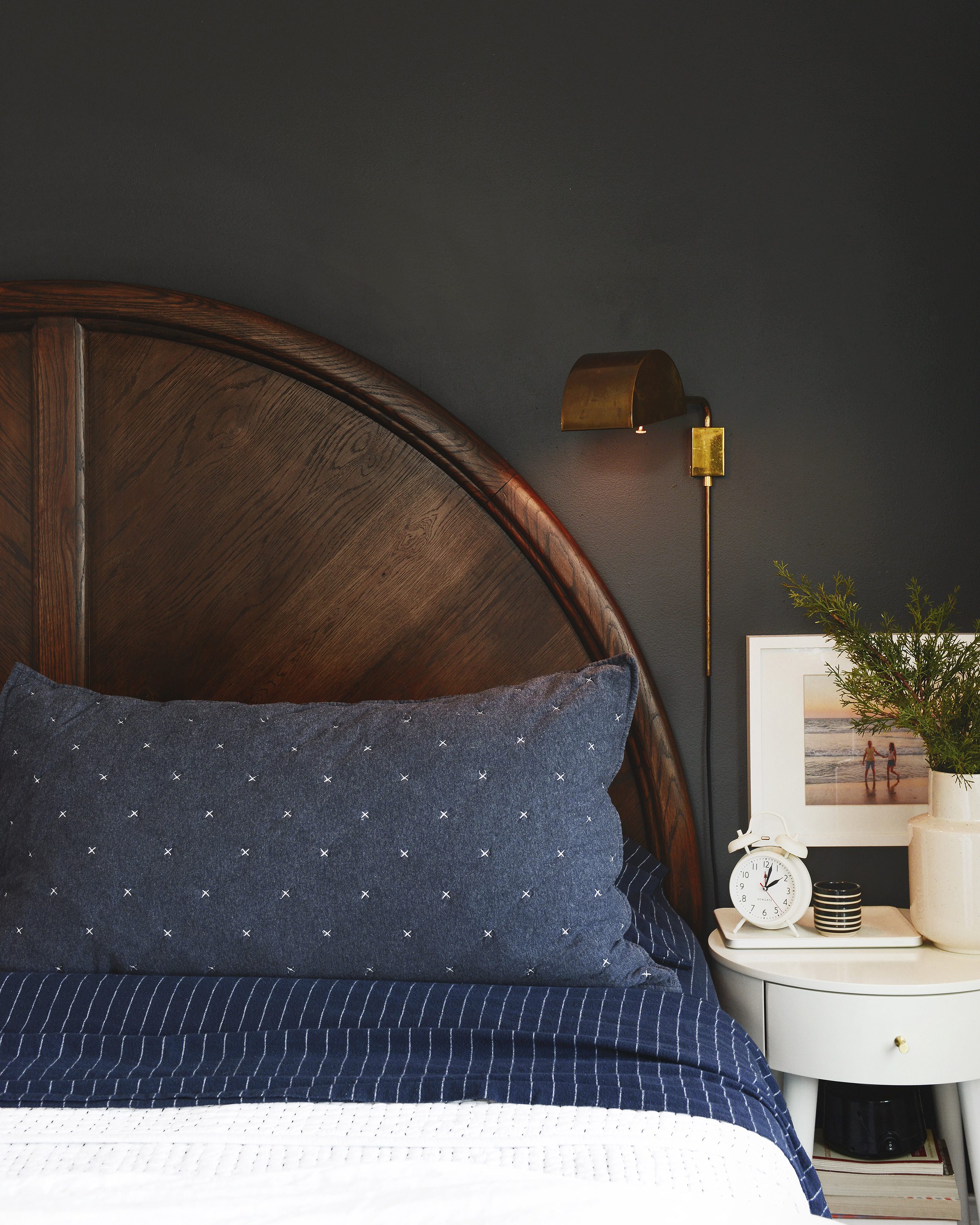 vignette of navy bedding and a round wooden headboard | via Yellow Brick Home