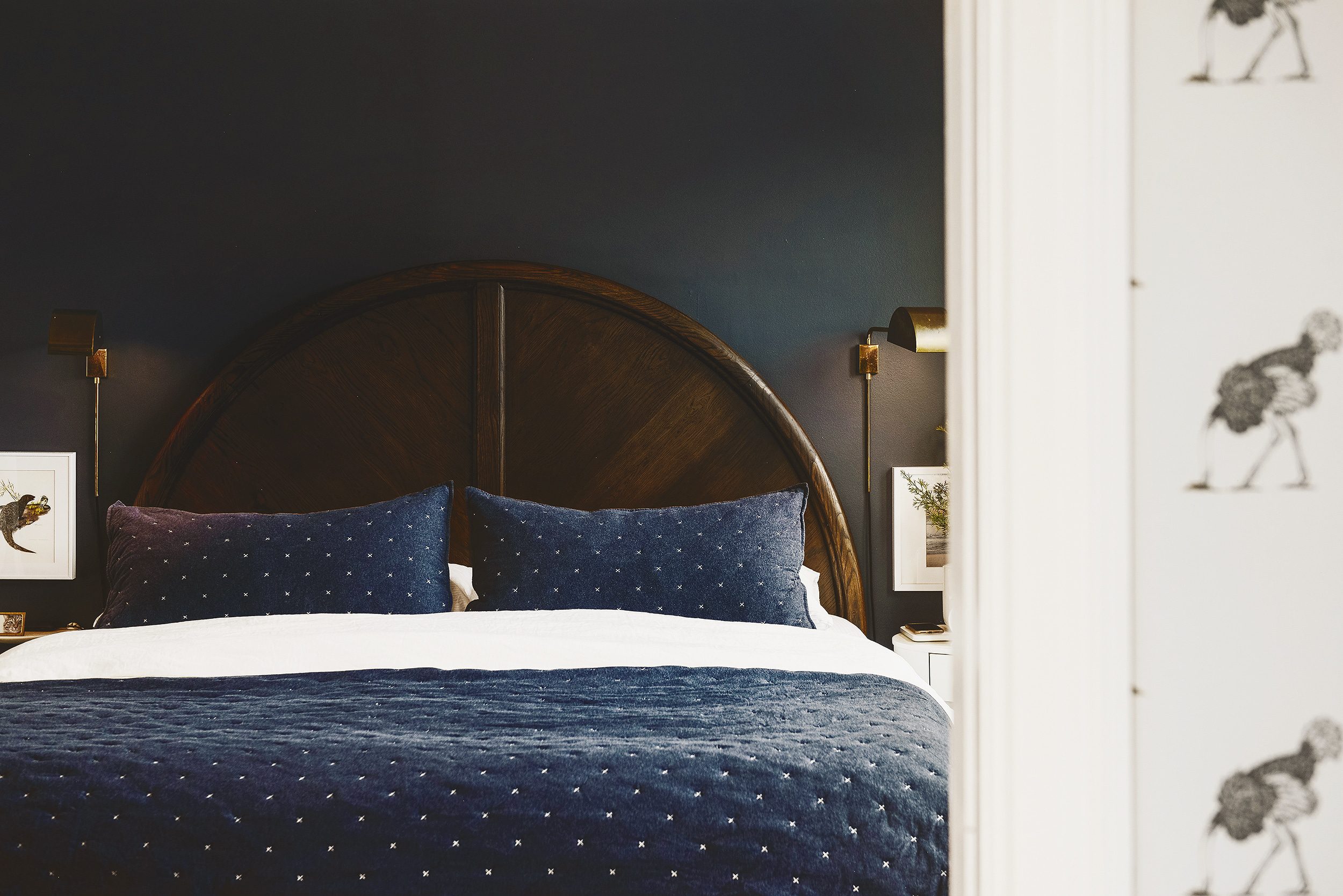 A moody bedroom with navy bedding and a large half-circle headboard | via Yellow Brick Home