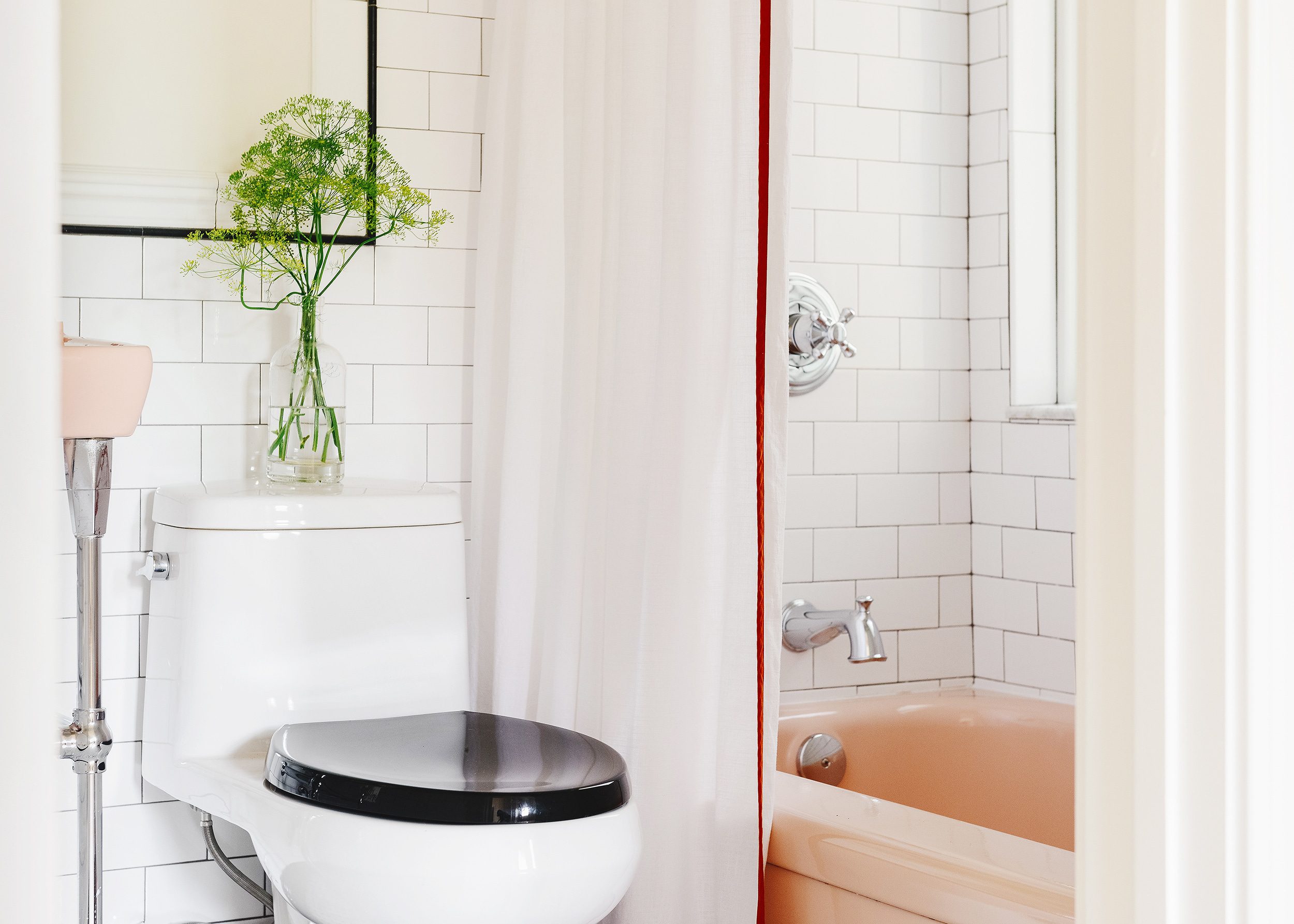 A small white bathroom with classic subway tile and a vintage pink bathtub | via Yellow Brick Home