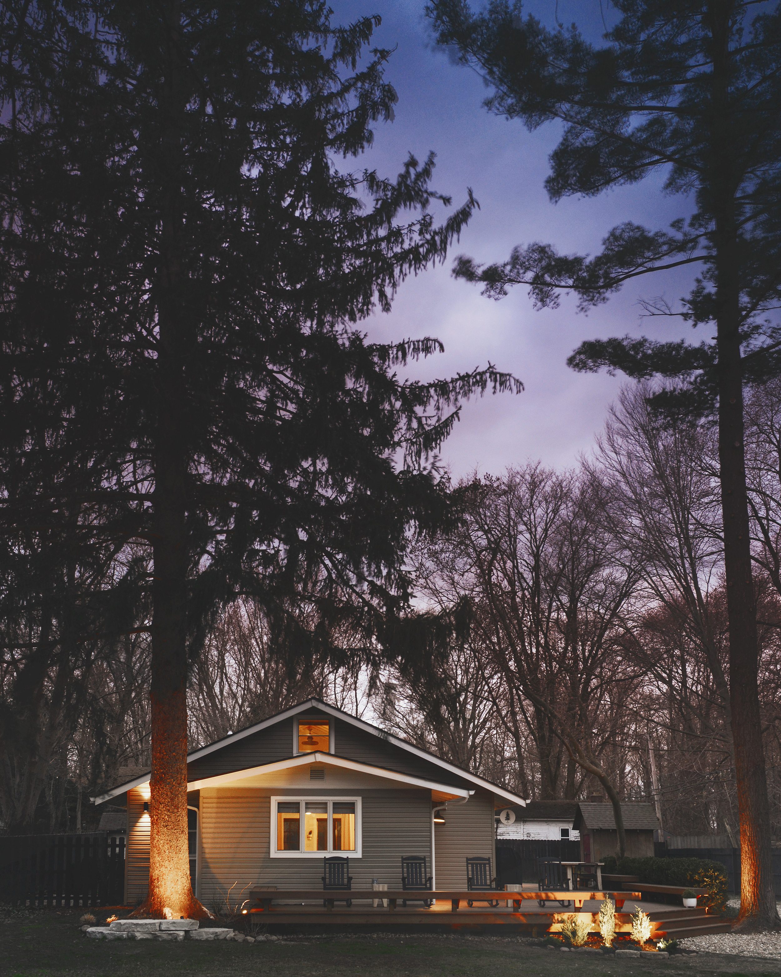 A straight on view of Tree House at night, with blue and purple skies and landscape lighting, via Yellow Brick Home