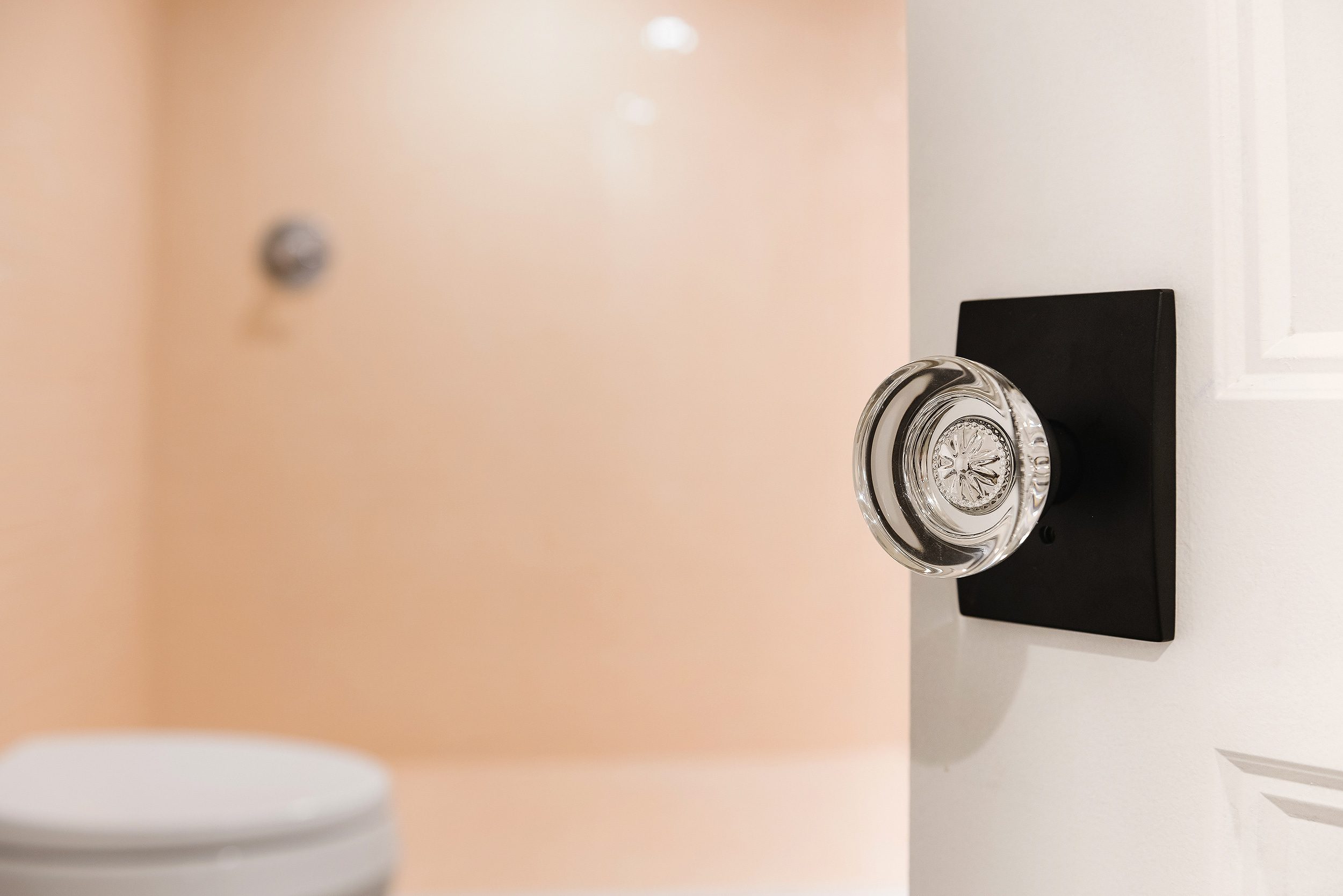 Schlage custom hobson glass knob detail, entering a bathroom with peachy-pink tile | via Yellow Brick Home