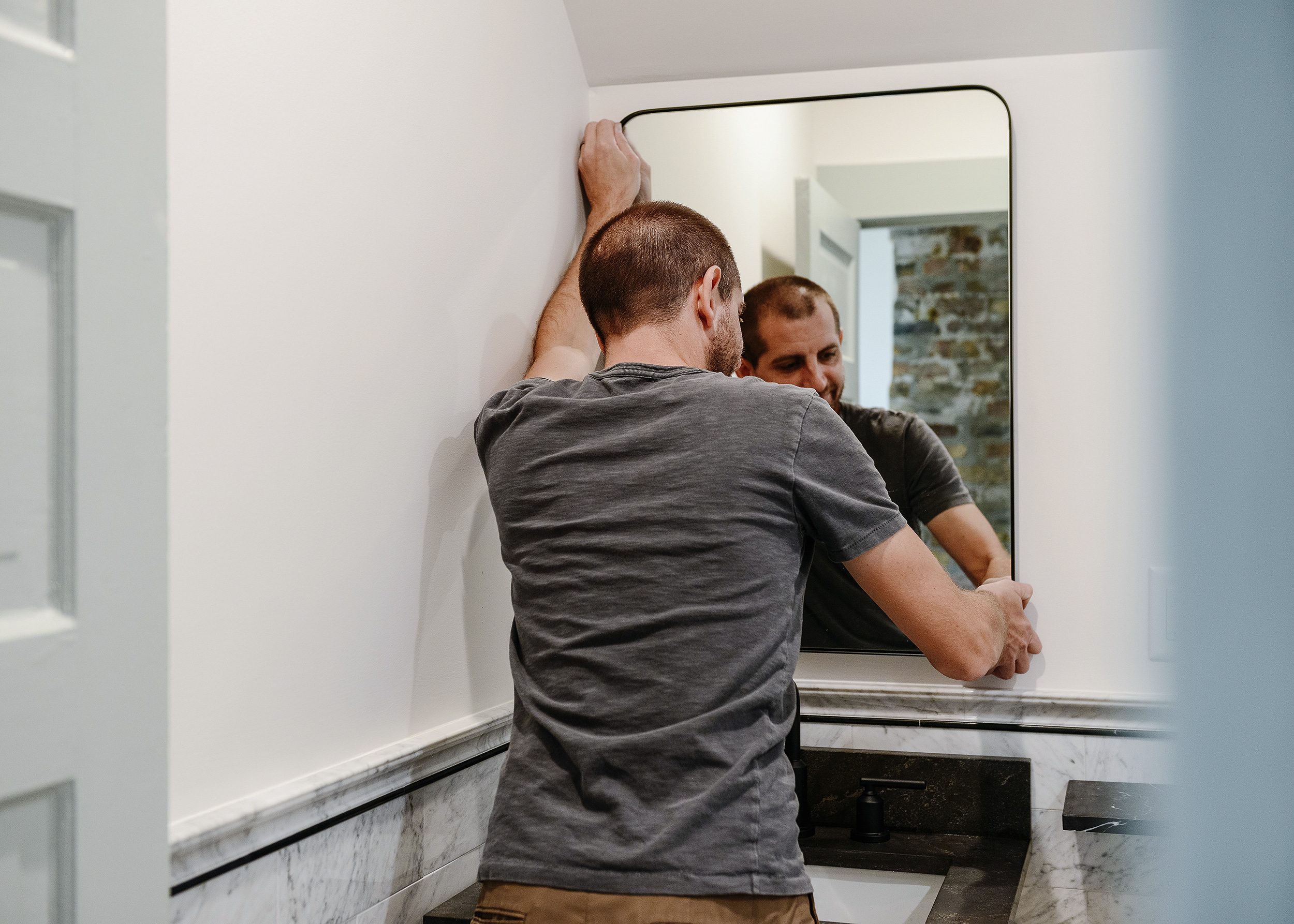 Scott hanging the mirror on our 3M CLAWs | via Yellow Brick Home