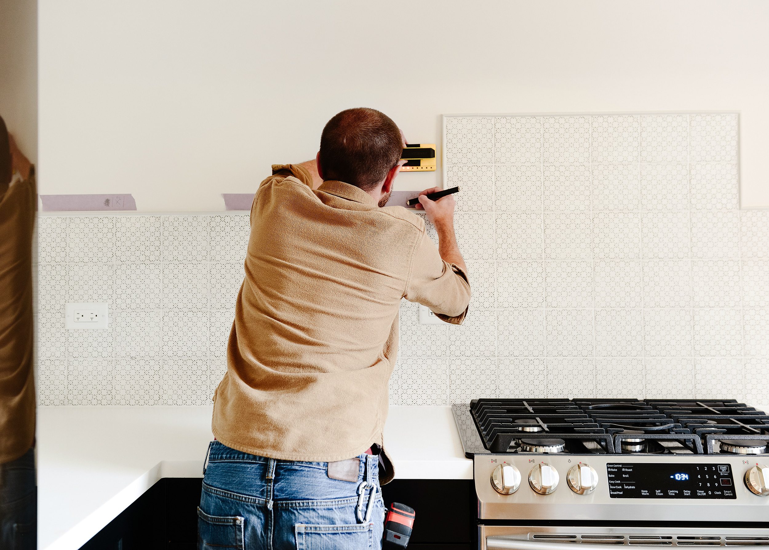 Marking studs in a kitchen to prepare for open shelving | via Yellow Brick Home