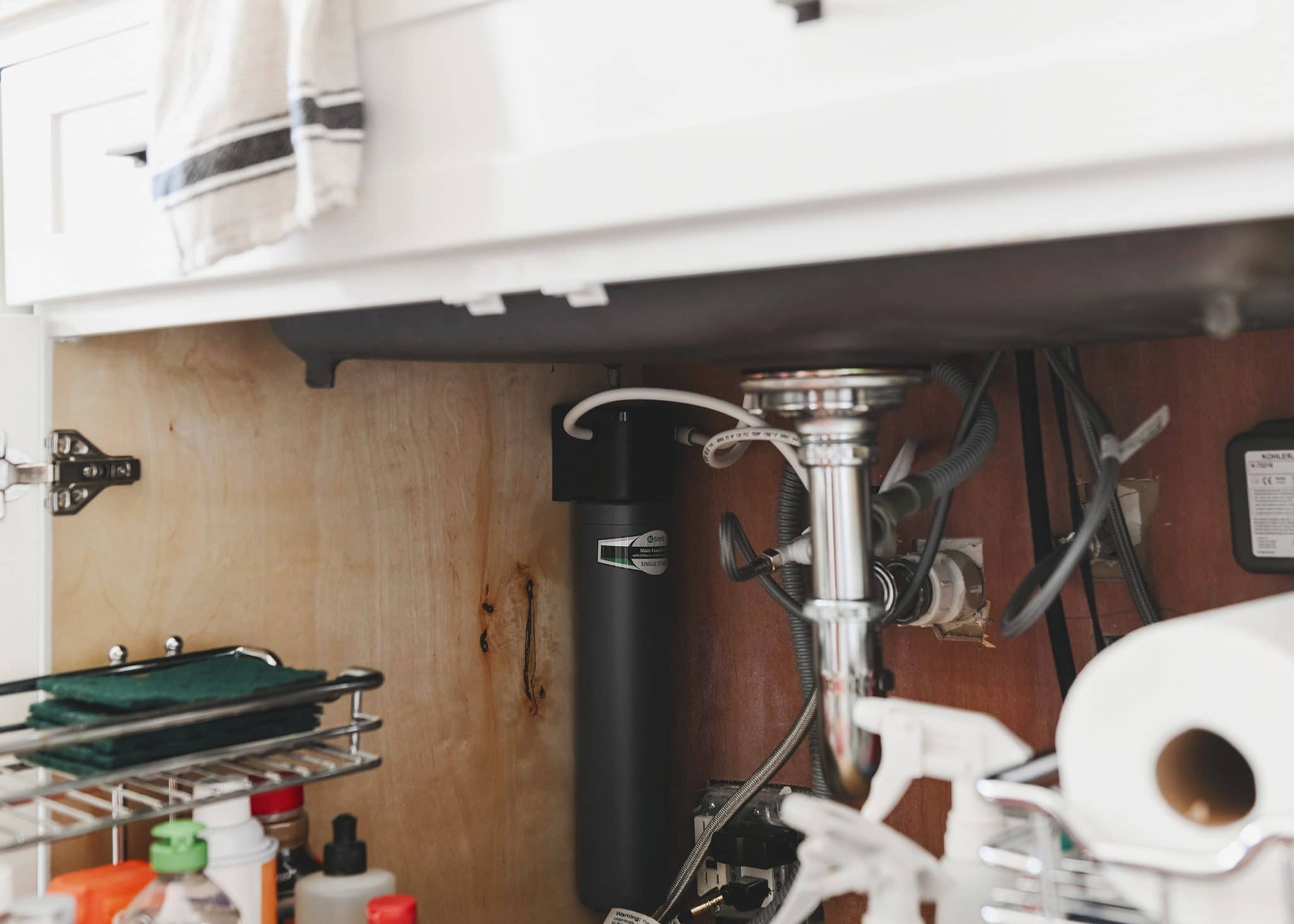 An A.O. Smith main faucet water filter is installed under a kitchen sink // via Yellow Brick Home