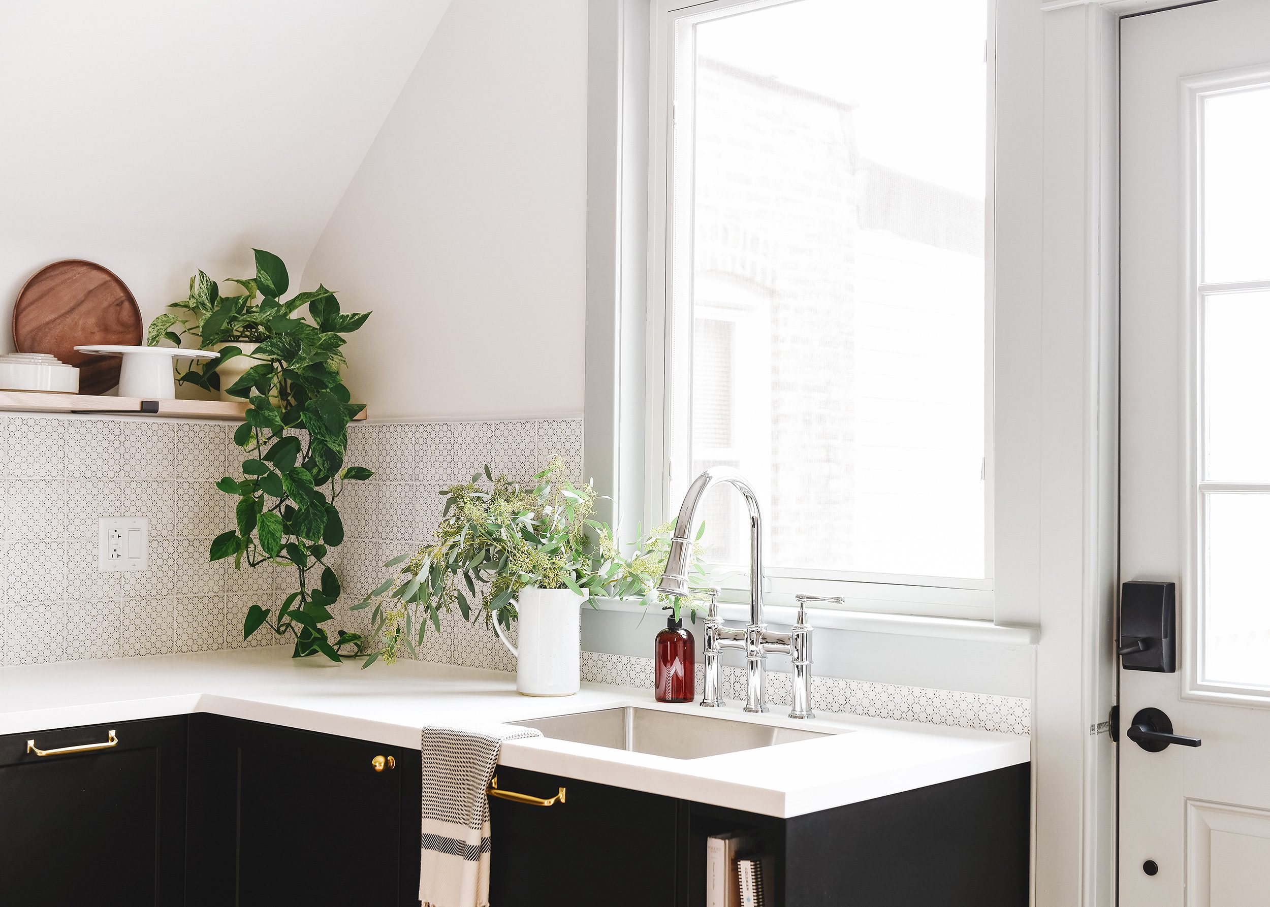 Small kitchen inspiration: Black base cabinets with floating shelves above a white countertop, polished chrome Elkay faucet and stainless steel sink. | via Yellow Brick Home