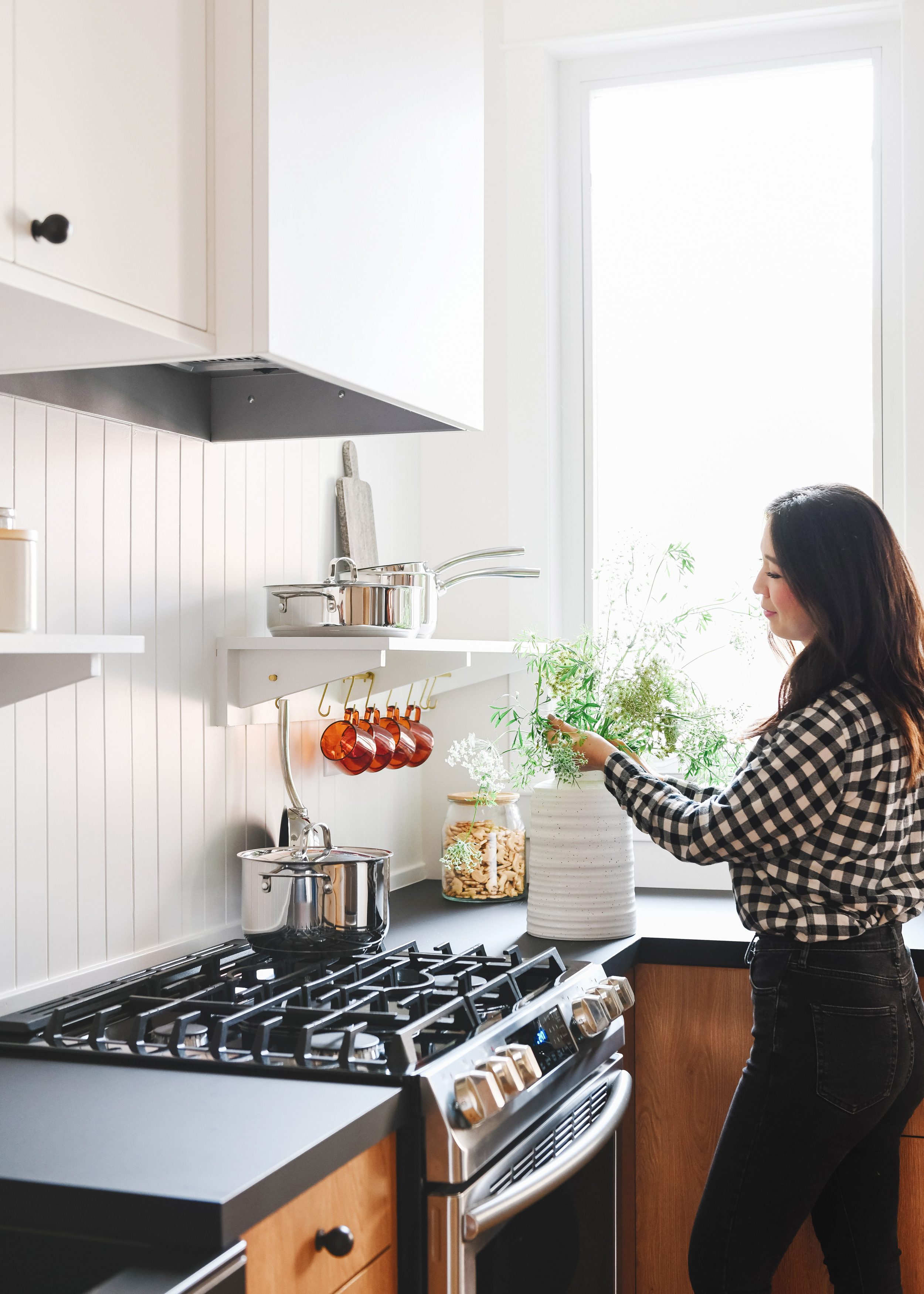 Kim putting together a vase of stems in a white, wood and black kitchen | via Yellow Brick Home