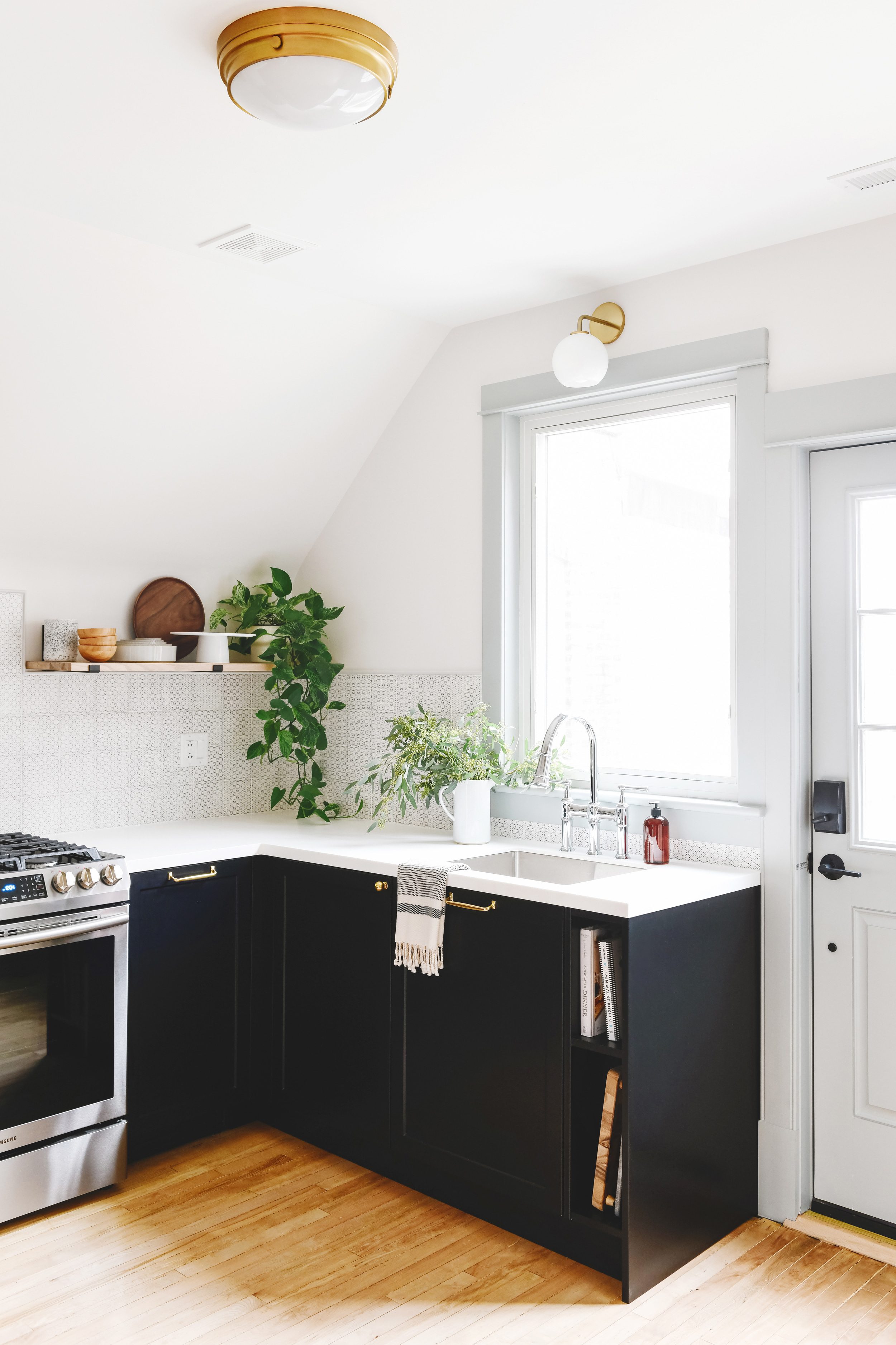 A small kitchen with black lower cabinets, gray-blue upper cabinets and floating shelves | via Yellow Brick Home