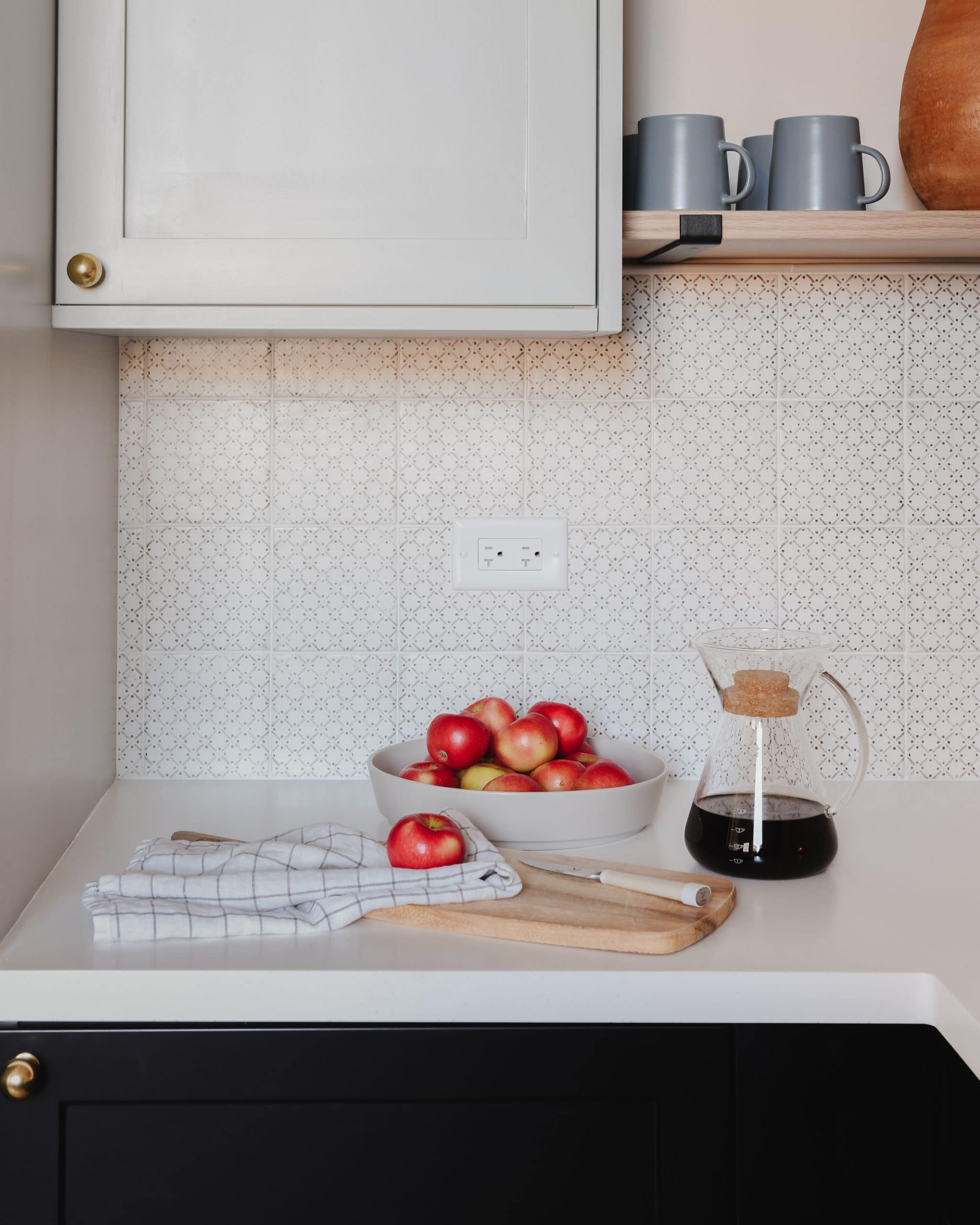 Black kitchen cabinets, white countertop and patterned tile backsplash, styled with apples and coffee | via Yellow Brick Home