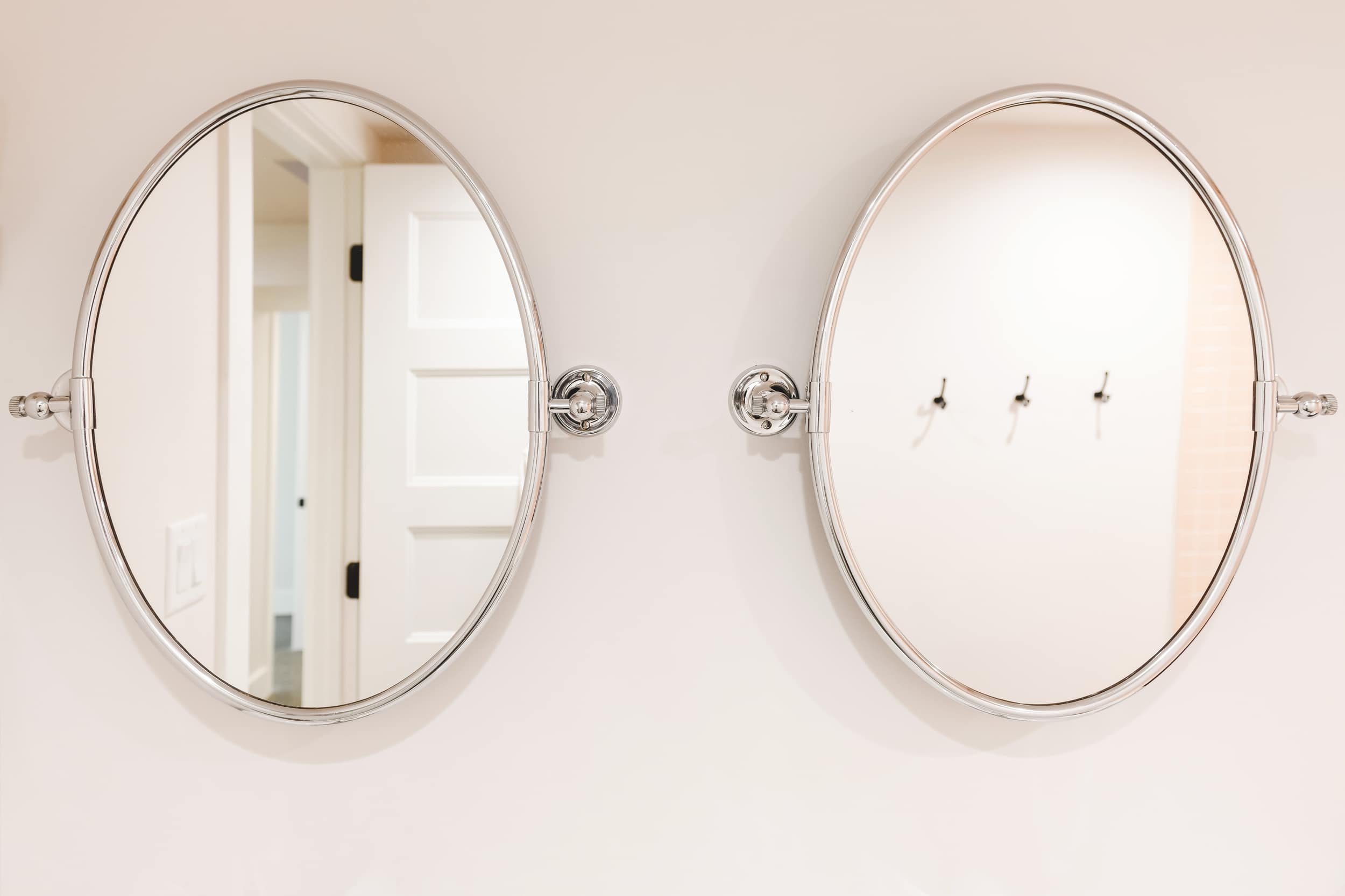a pair of chrome pivot mirrors on a white wall | Two Flat den bathroom before + after! | via Yellow Brick Home