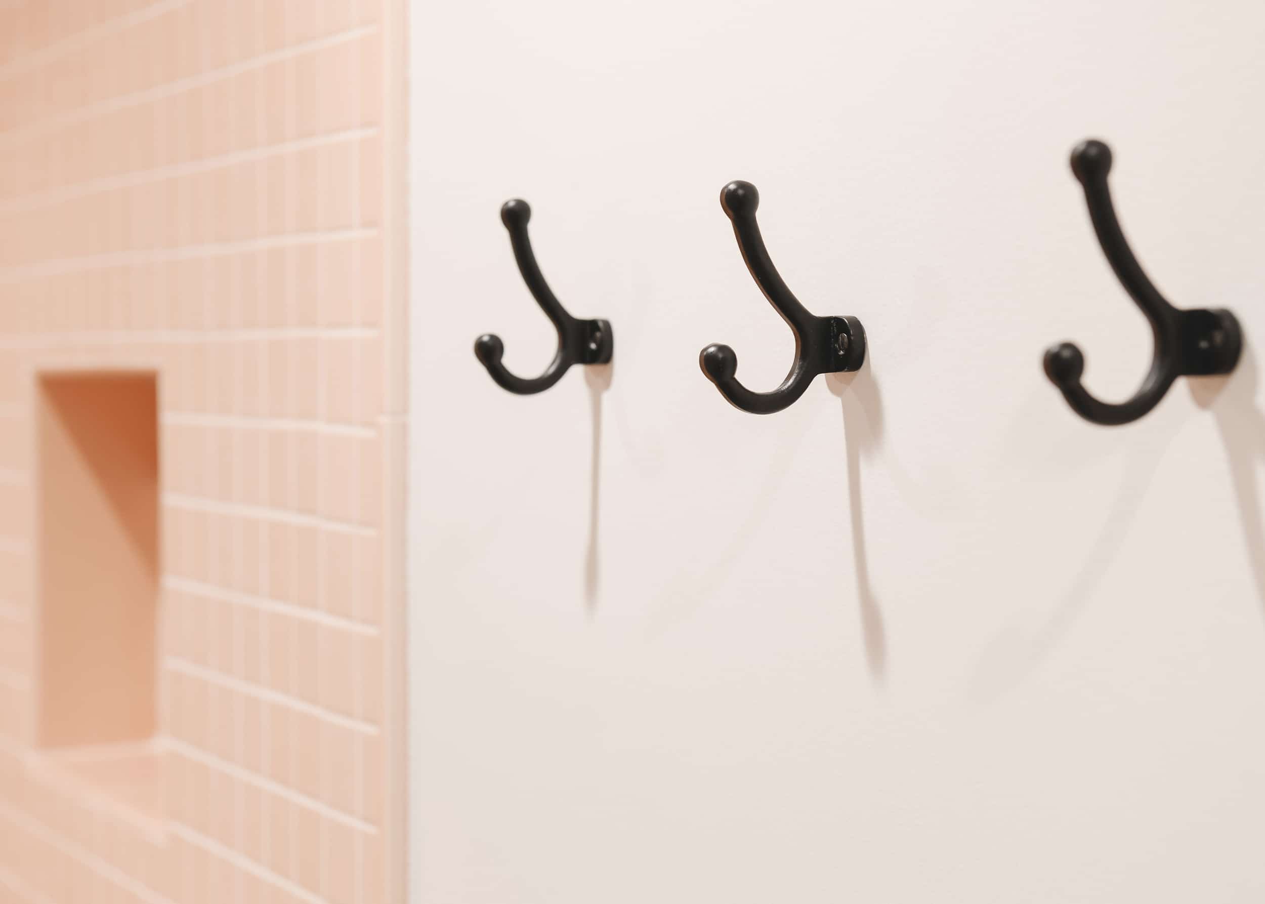 cast iron hooks with peachy pink tile in the background | Two Flat den bathroom before + after! | via Yellow Brick Home
