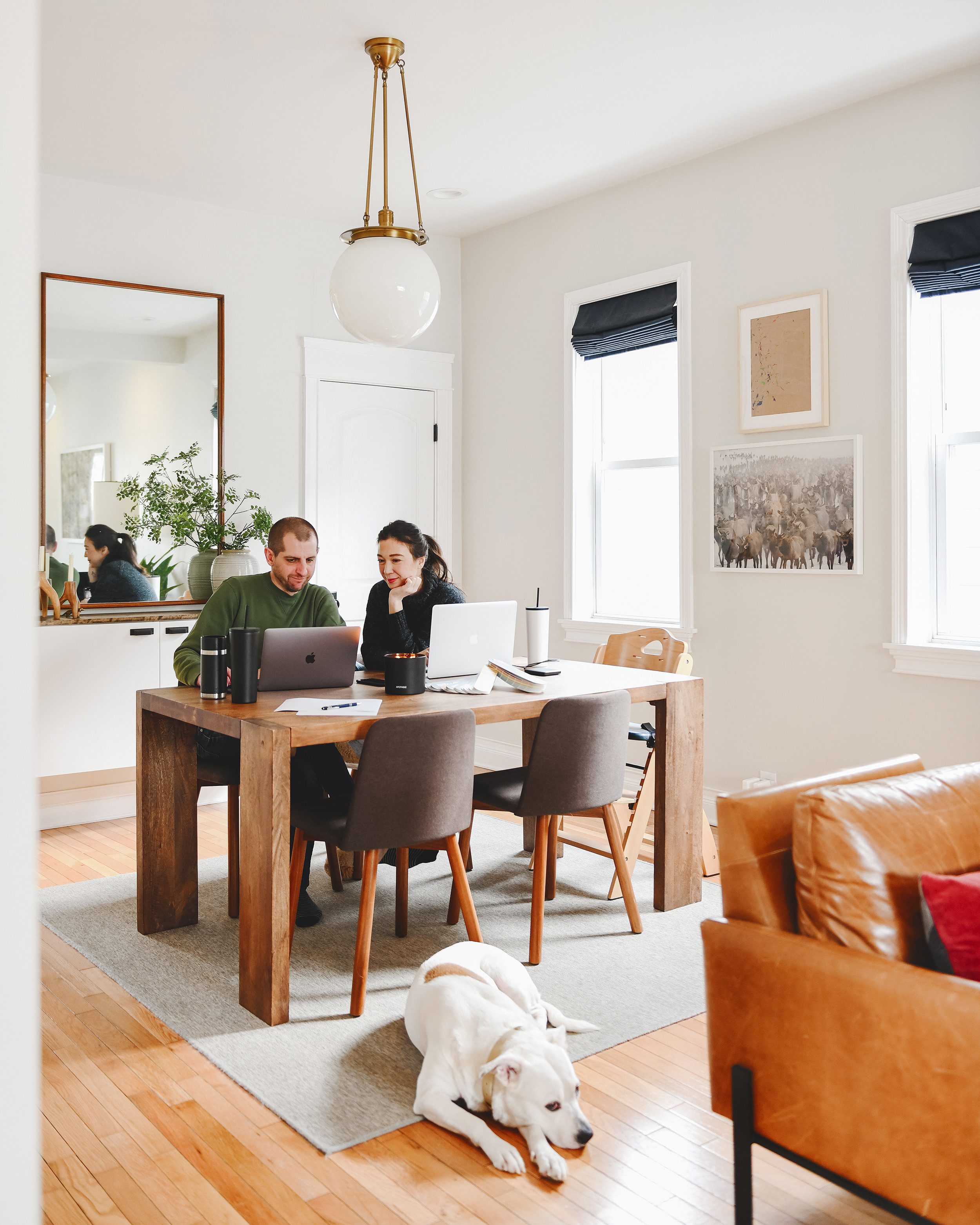 Kim and Scott work from the dining room table while Catfish the dog naps on the rug // via yellow brick home