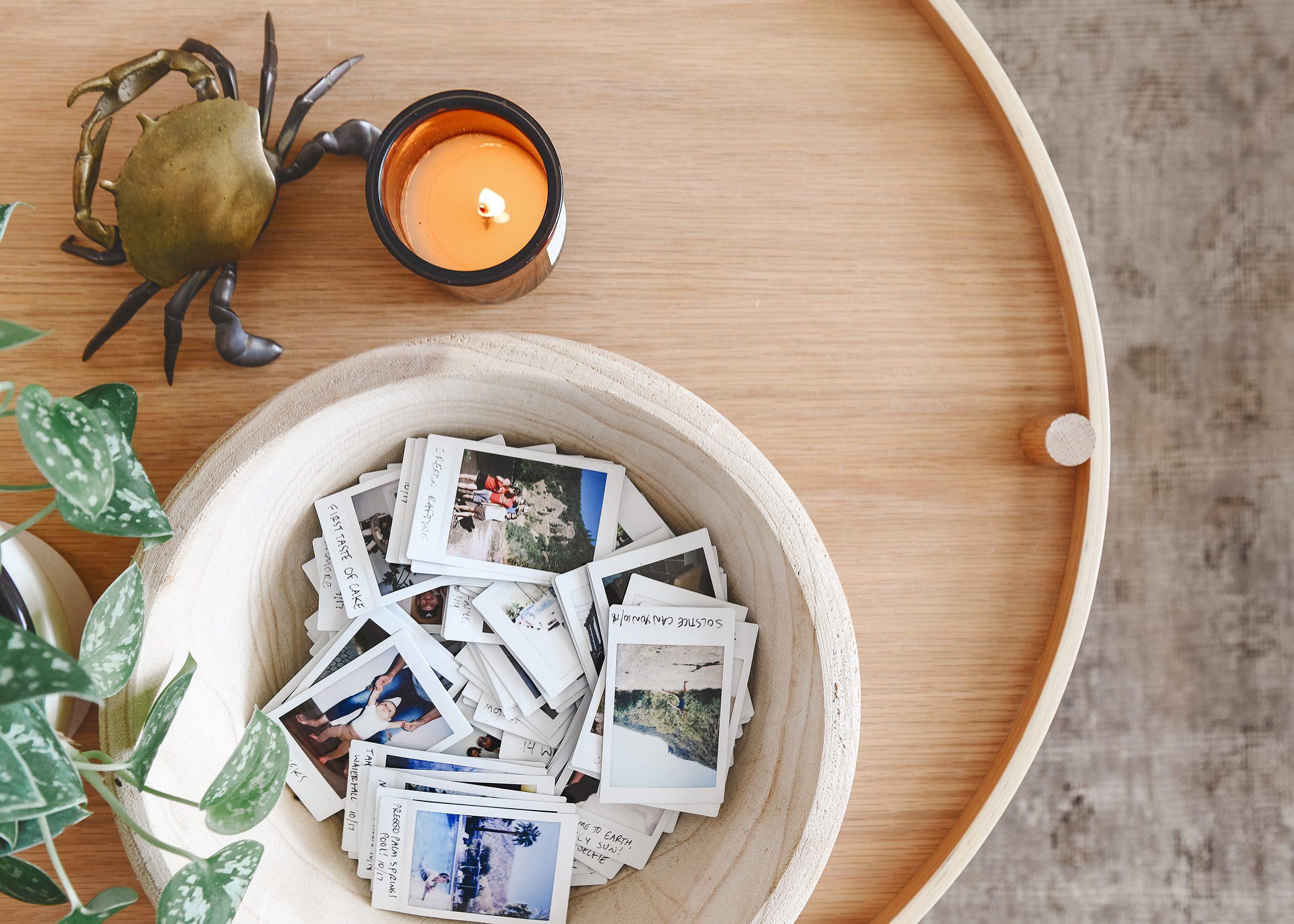 Detail of coffee table with bowl of Instax photos, candle and brass crab | via Yellow Brick Home, Big Bowls as Decor!