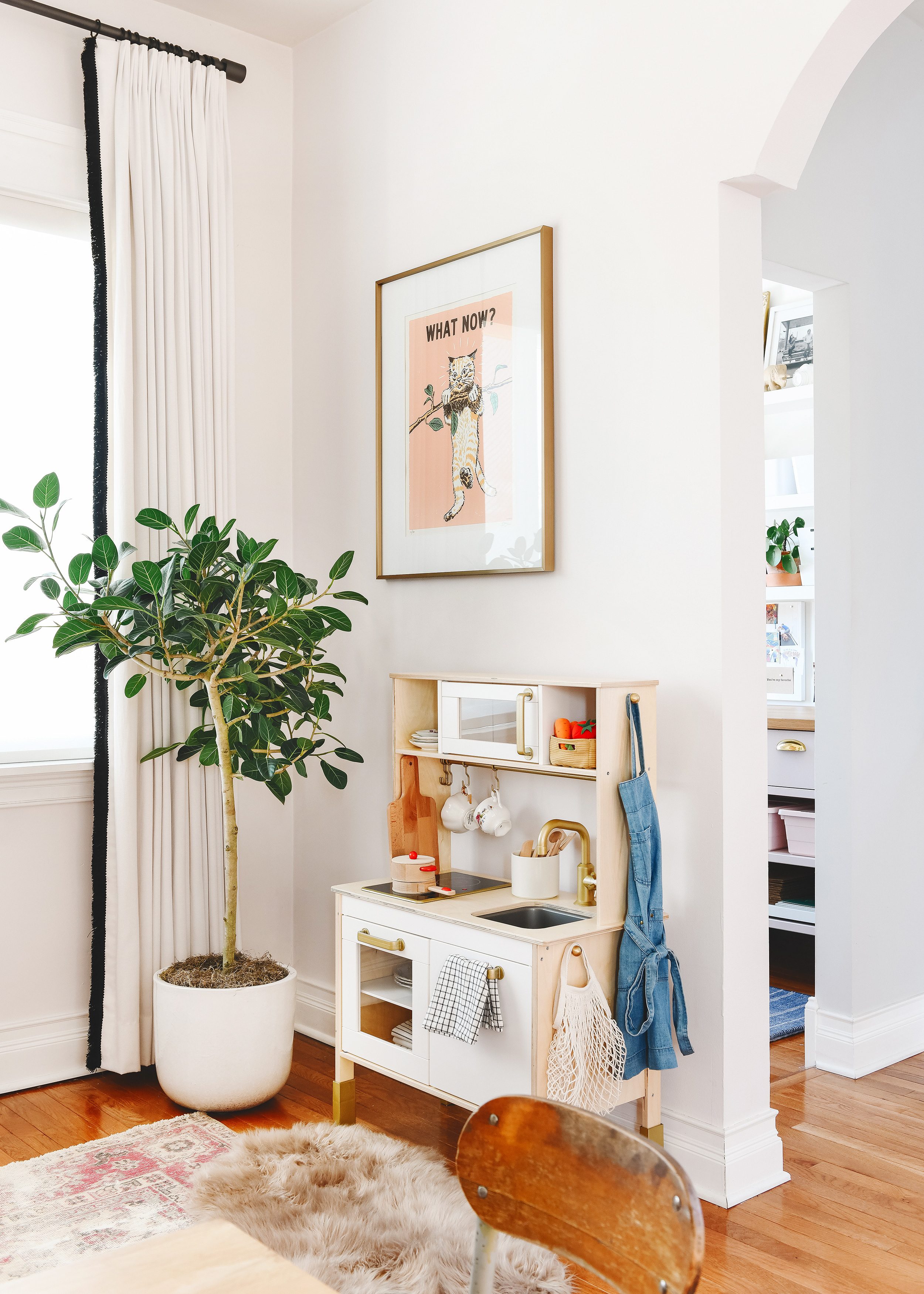 Tips for Stocking Your Play Kitchen + 36 of the Cutest Accessories! | A corner of Lucy's playroom showing her IKEA DUKTIG play kitchen with a Ficus Audrey plant and cat art print | via Yellow Brick Home