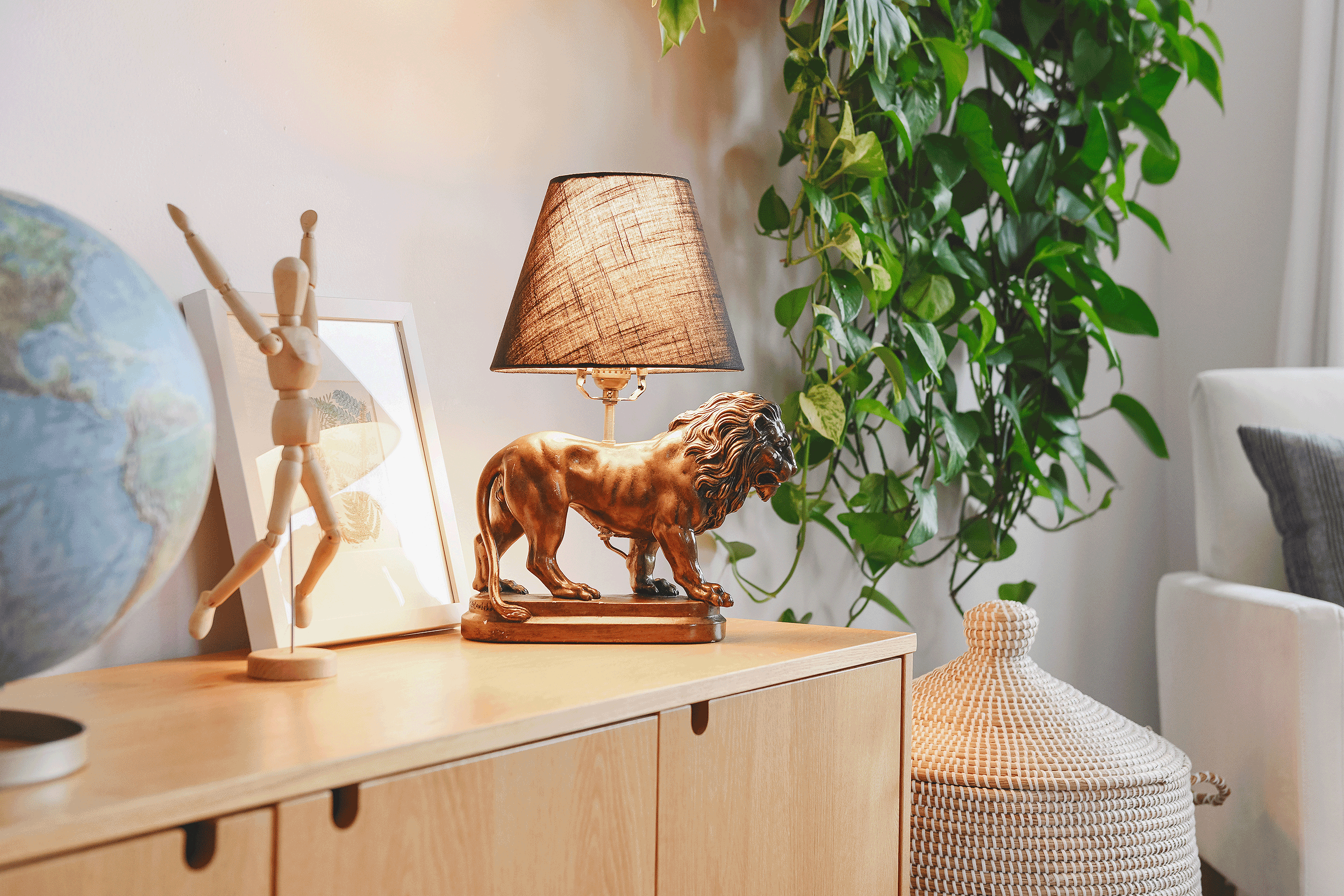 A GIF shows our DIY lion lamp lighting up the credenza in our playroom surrounded by plants and greenery // via Yellow Brick Home