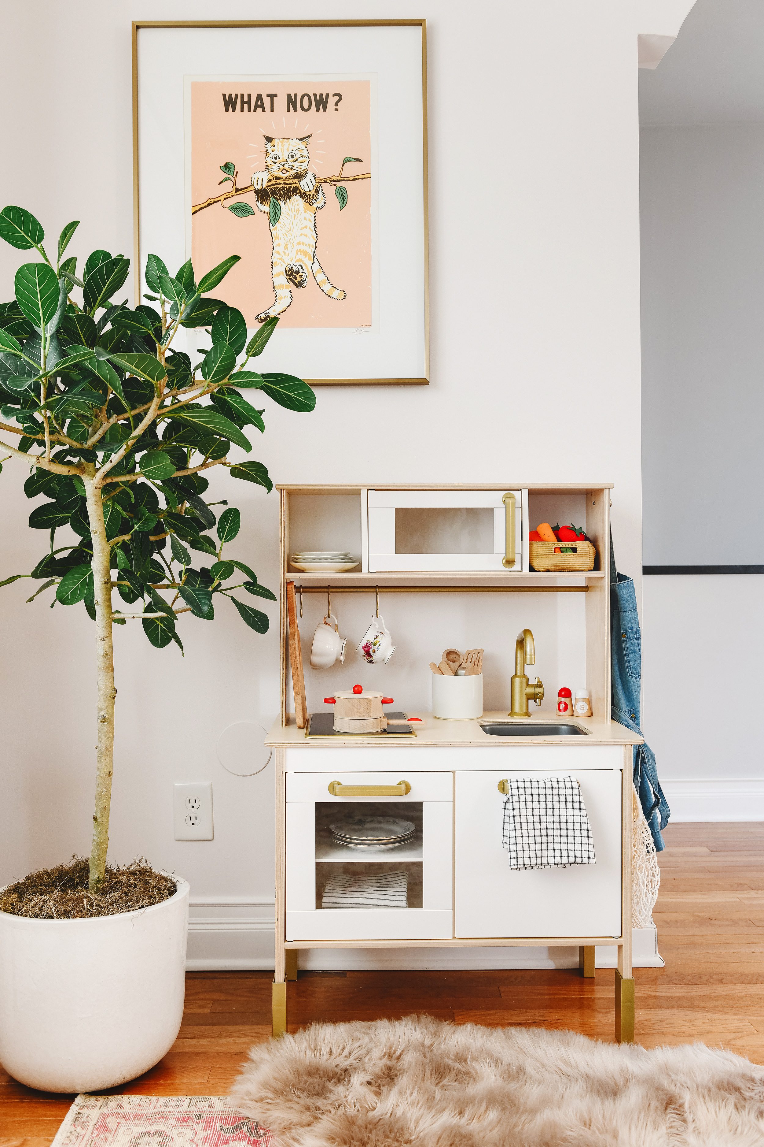 Tips for Stocking Your Play Kitchen + 36 of the Cutest Accessories! | A corner of Lucy's playroom showing her IKEA DUKTIG play kitchen with a cat art print hanging above | via Yellow Brick Home