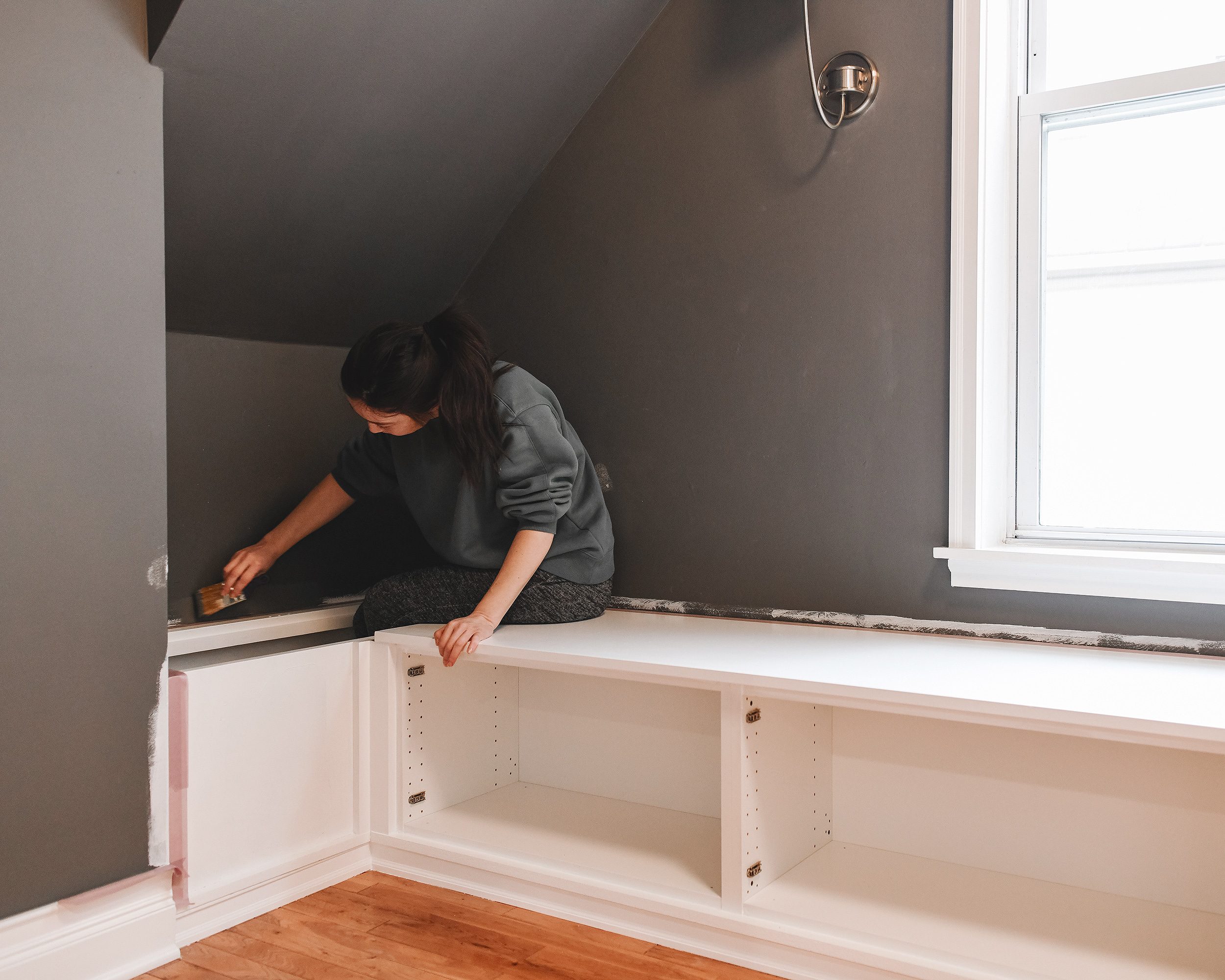 Kim finishes wall touch up paint surrounding the built-in storage seating // via Yellow Brick Home