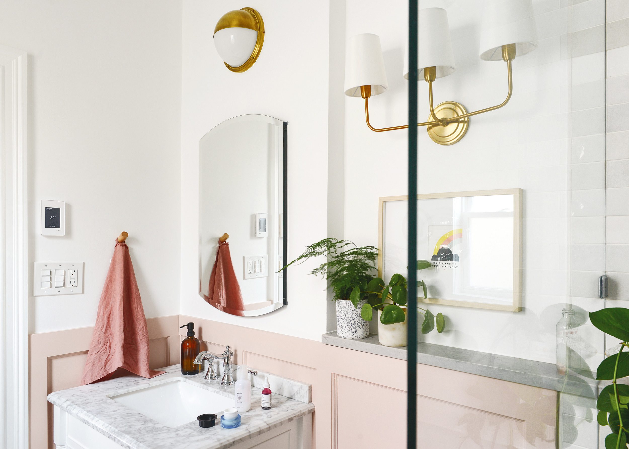 Our Chicago bathroom featuring pink board and batten, marble vanity top on a white vanity and brass light fixtures // via Yellow Brick Home