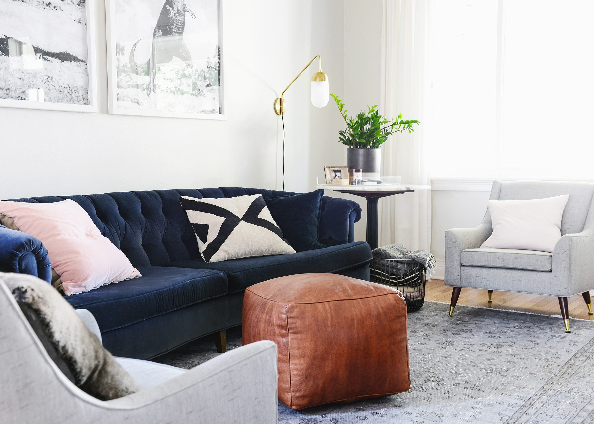 Navy velvet sofa and vintage rug with leather pouf | via Yellow Brick Home
